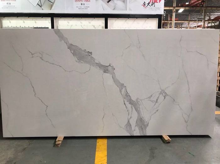  A large slab of white marble with prominent grey veining, standing in a showroom. The marble features dramatic, natural vein patterns, making it ideal for high-end interior or architectural projects.