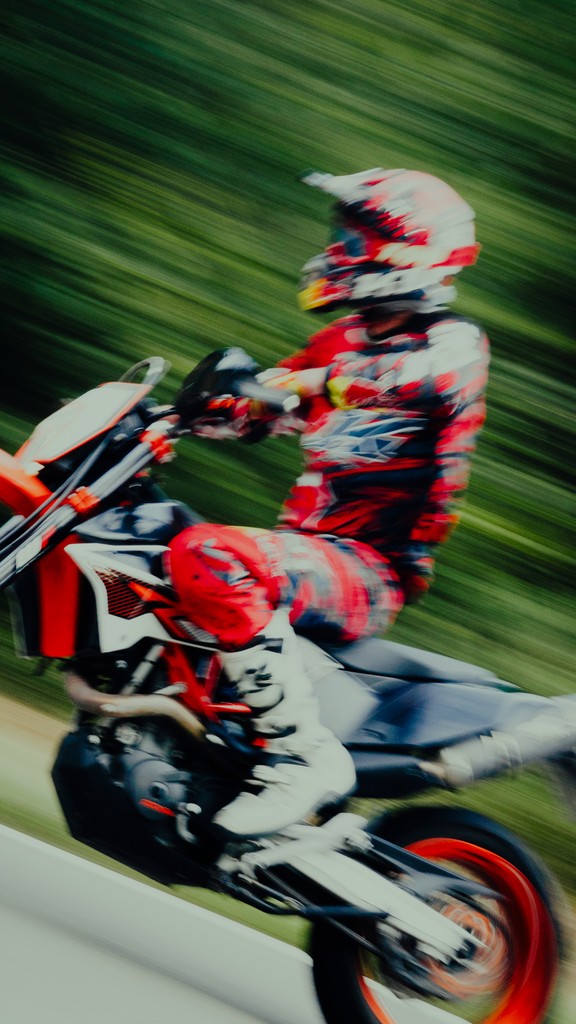 Blurred image of a motorcyclist riding through a green environment