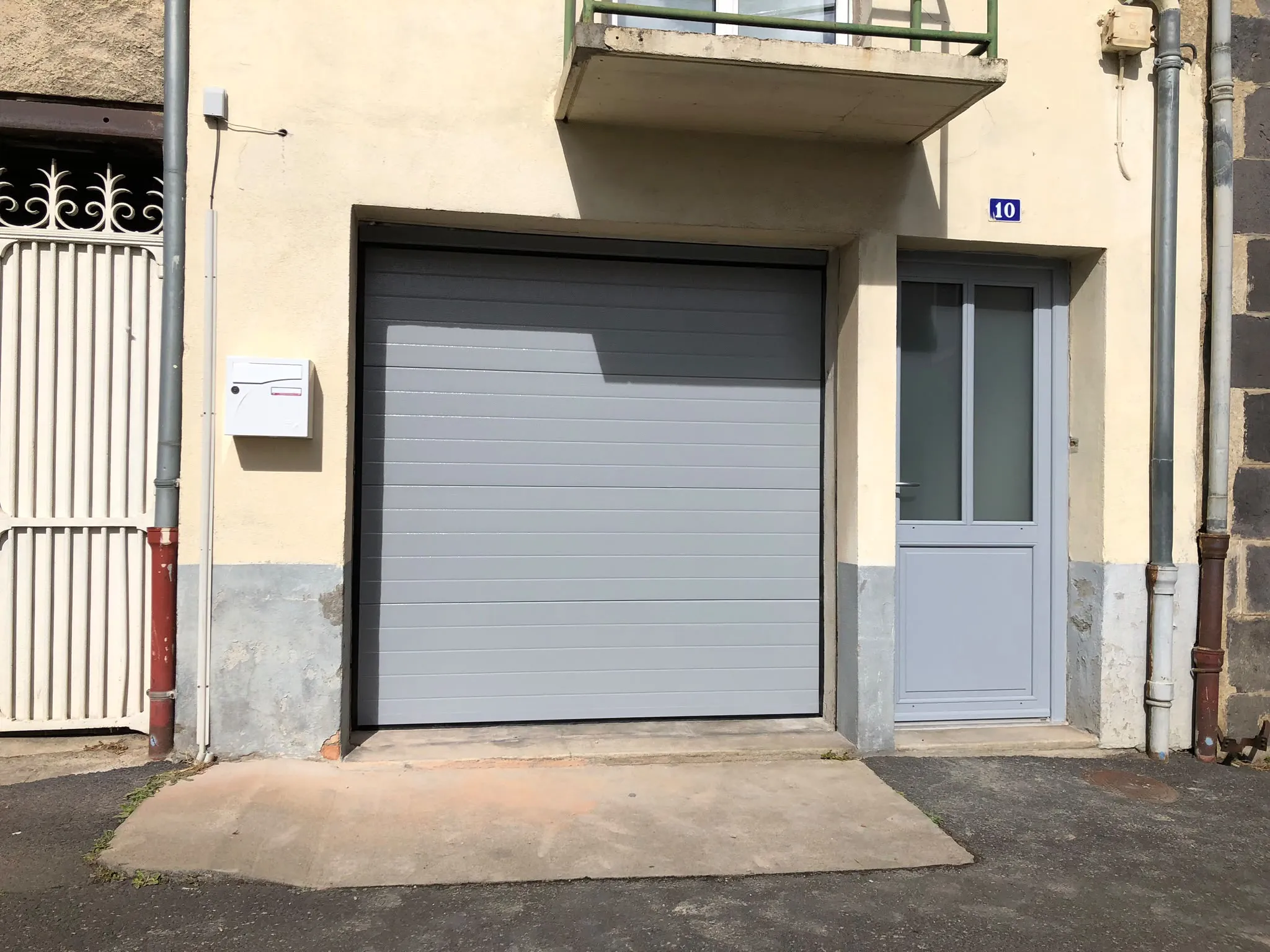Porte de garage grise sur une façade claire — AFermetures