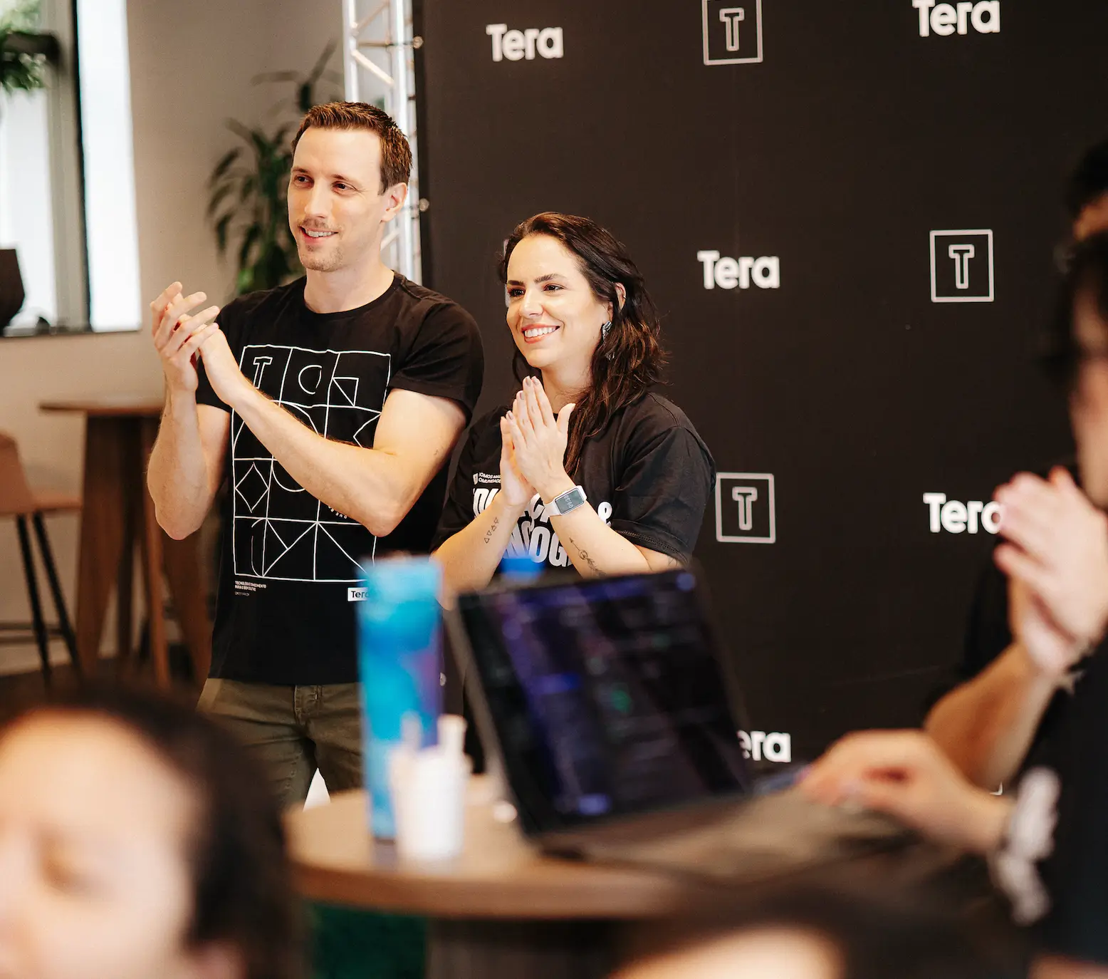 Participantes em evento da Tera aplaudindo apresentação sobre Inteligência Artificial, reunindo AI Builders e profissionais aprendendo a aplicar IA na prática.