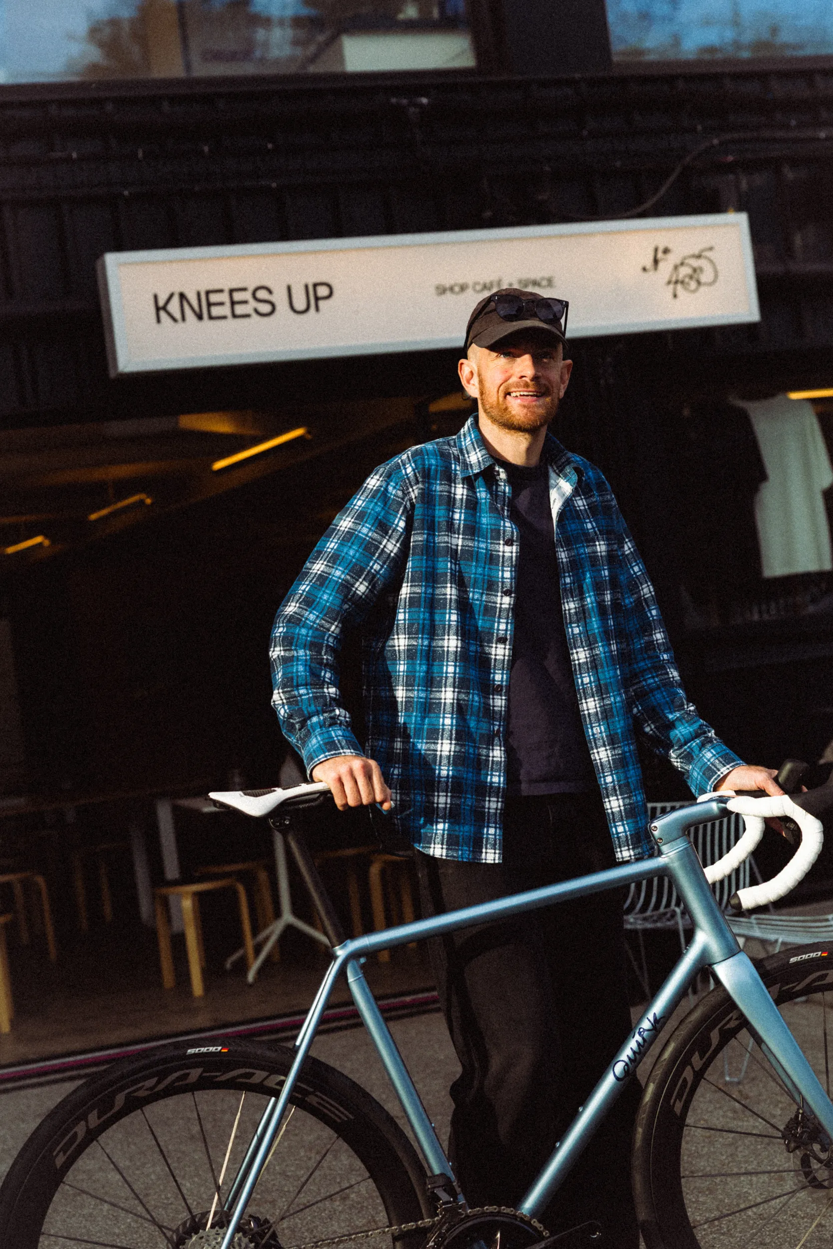 Oli Hooson standing in front of Knees Up shop with his Quirk Cycles Durmitor in Azzurro Hyperion.