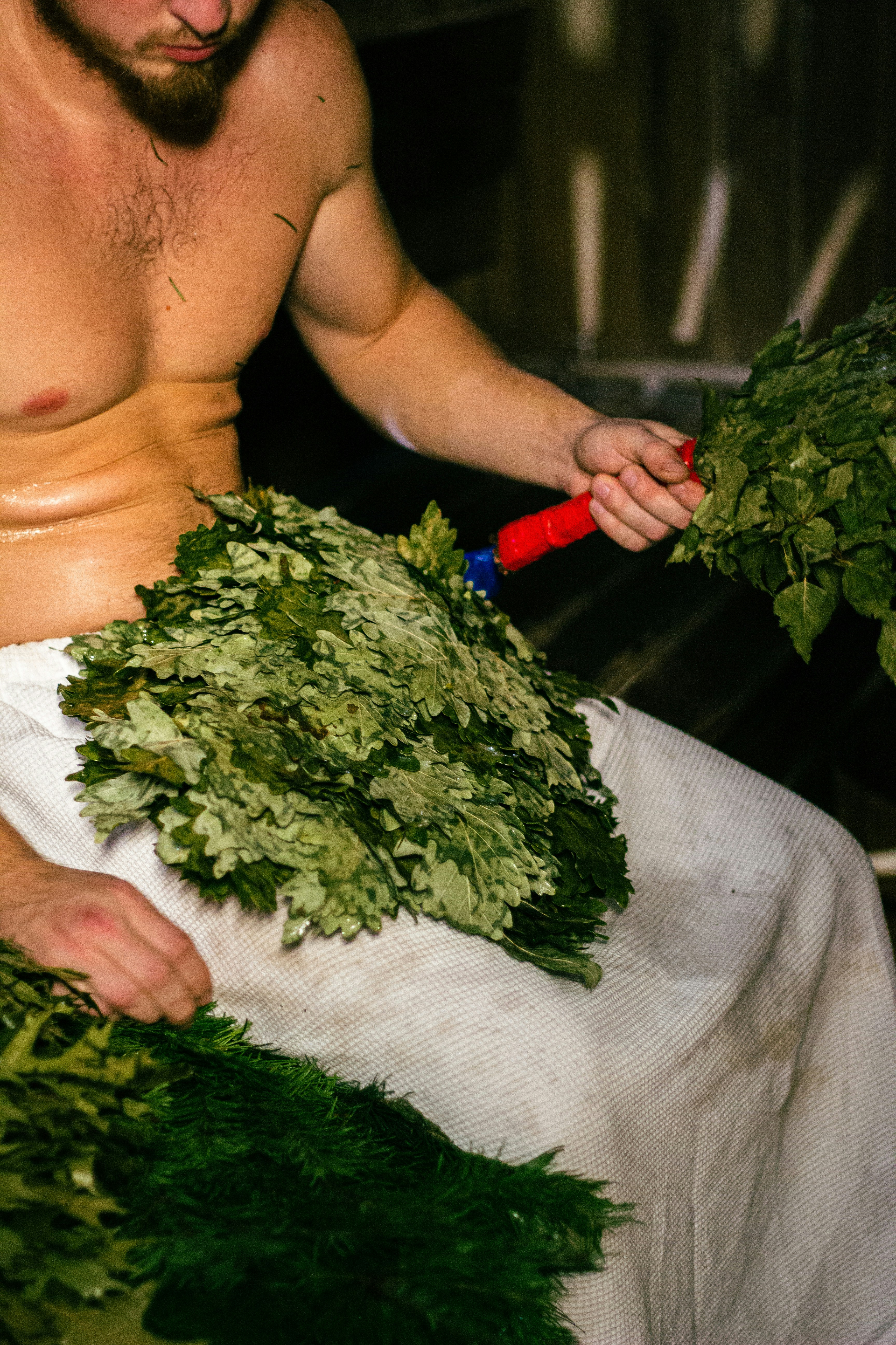 a shirtless man holding a bunch of greens