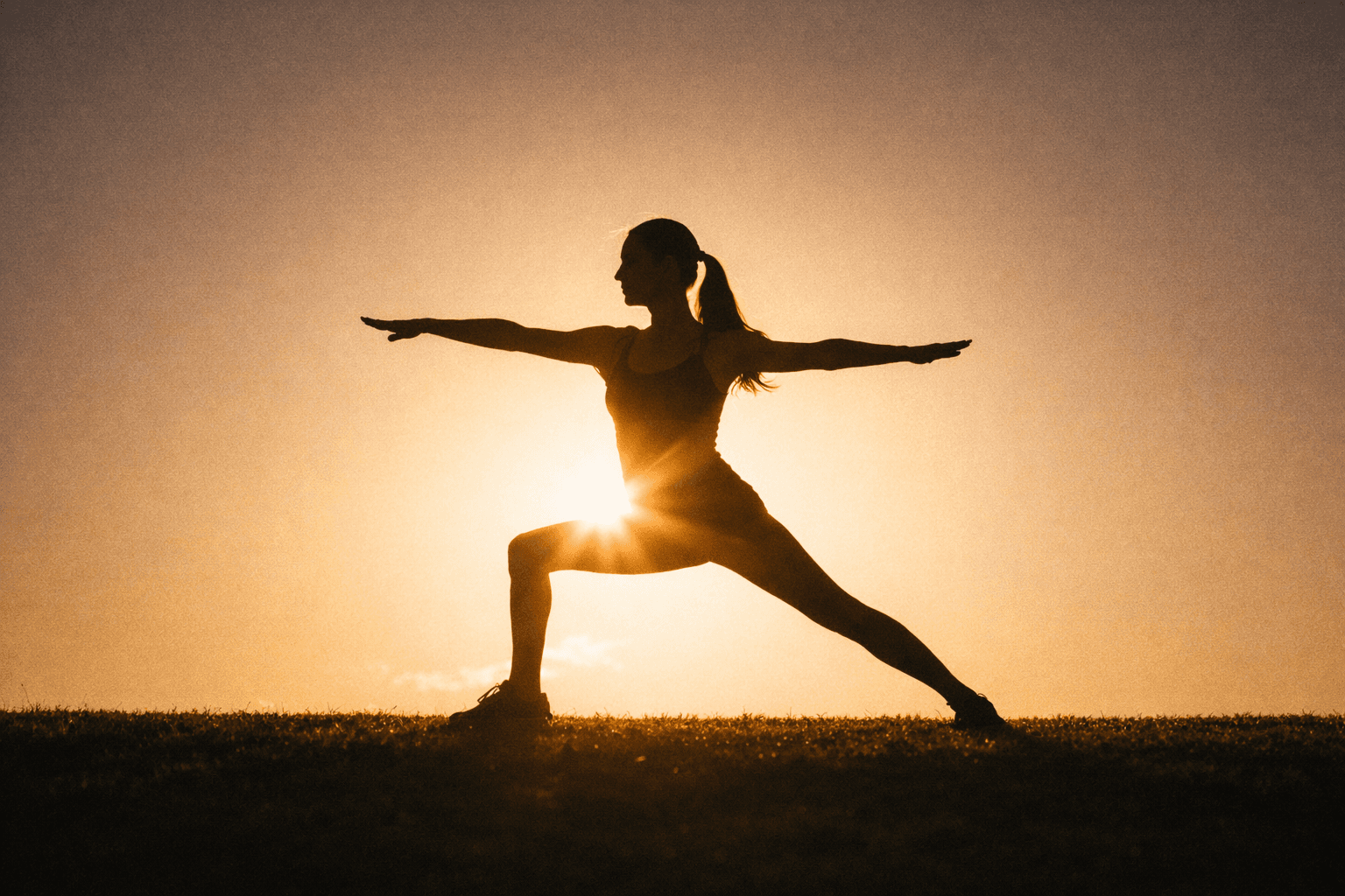 Silhouette of a person in a warrior yoga pose against a glowing sunset background.