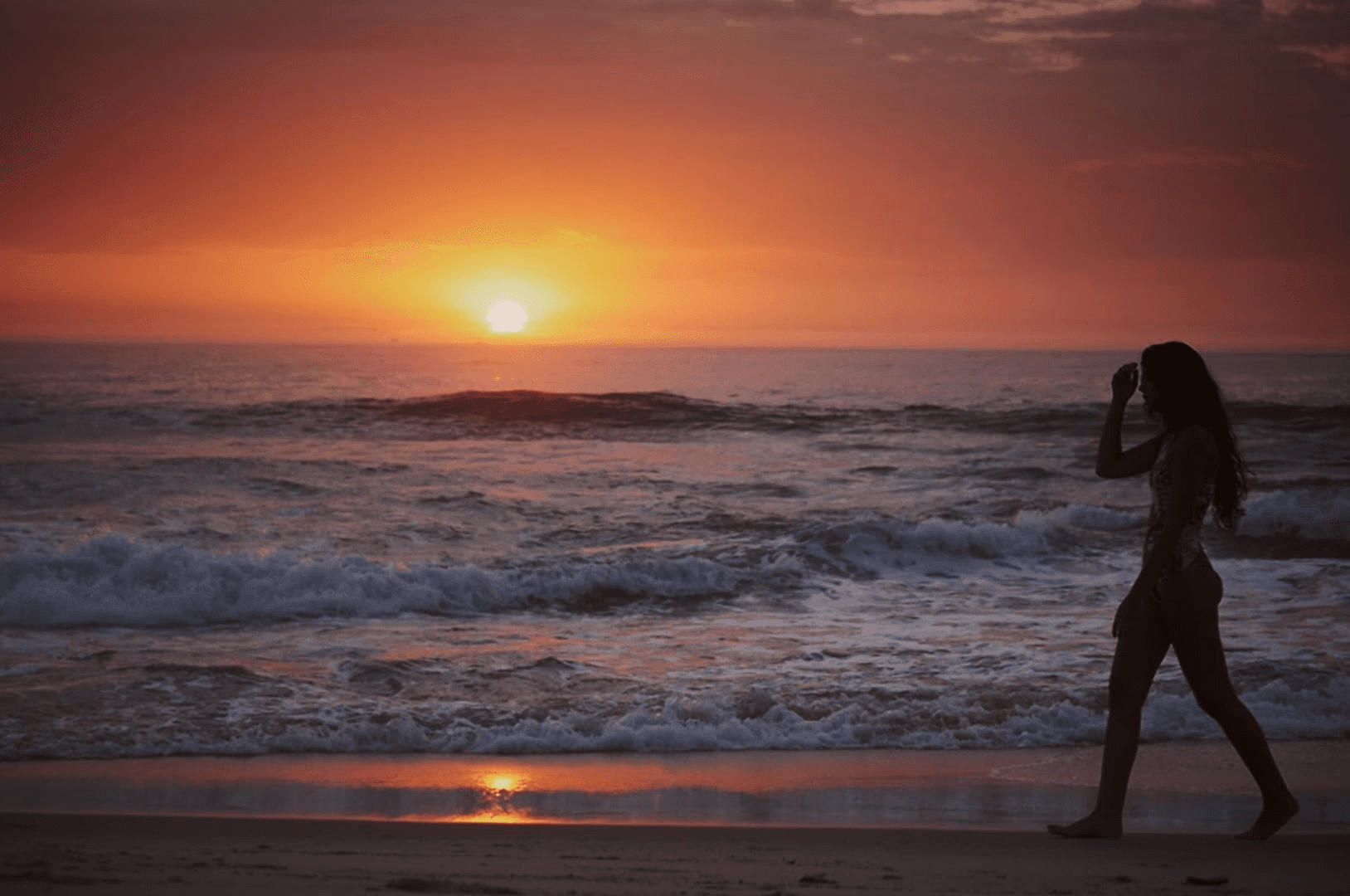 Editorial fashion photography of a woman at the beach wearing a bikini during the sunrise