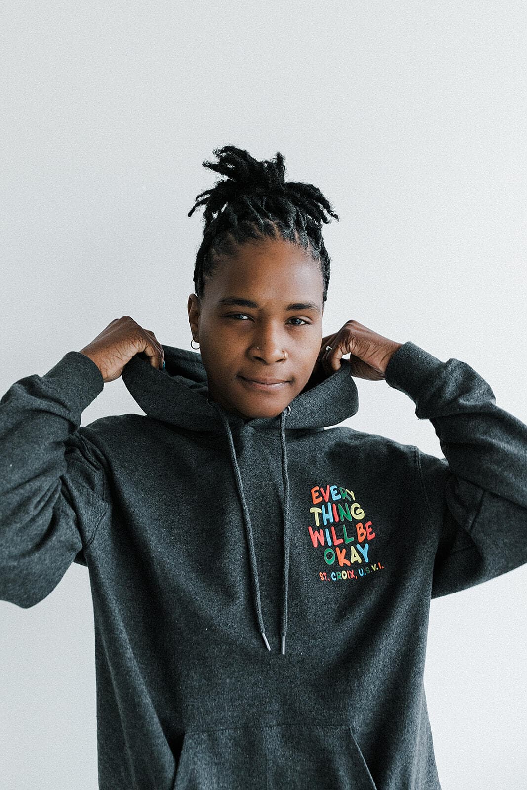 A model wearing a hoodie that reads ‘Everything Will Be Okay’ poses at Revelator Studio in Shreveport, showcasing the studio’s natural light and modern setting, perfect for creative photoshoots.