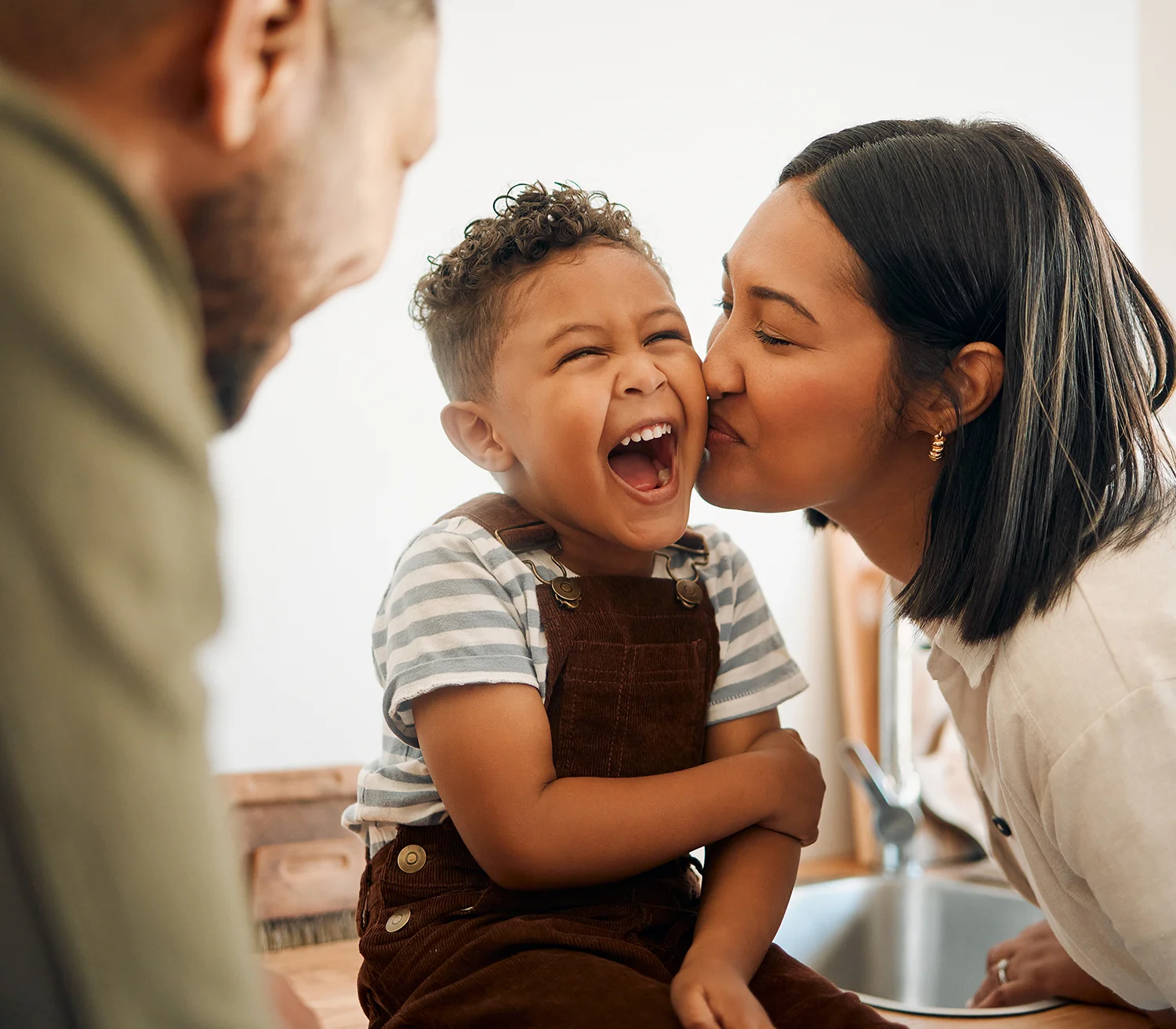 A happy family. Mum is kissing a young boy on the cheek.
