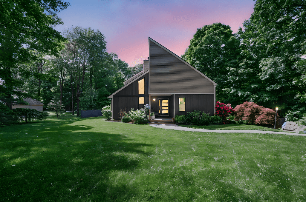 Spacious, luxurious living room with high ceilings, an elegant beige sectional sofa, warm ambient lighting, classical artwork, and rustic architectural elements, featuring an open layout with a view of a mezzanine level.