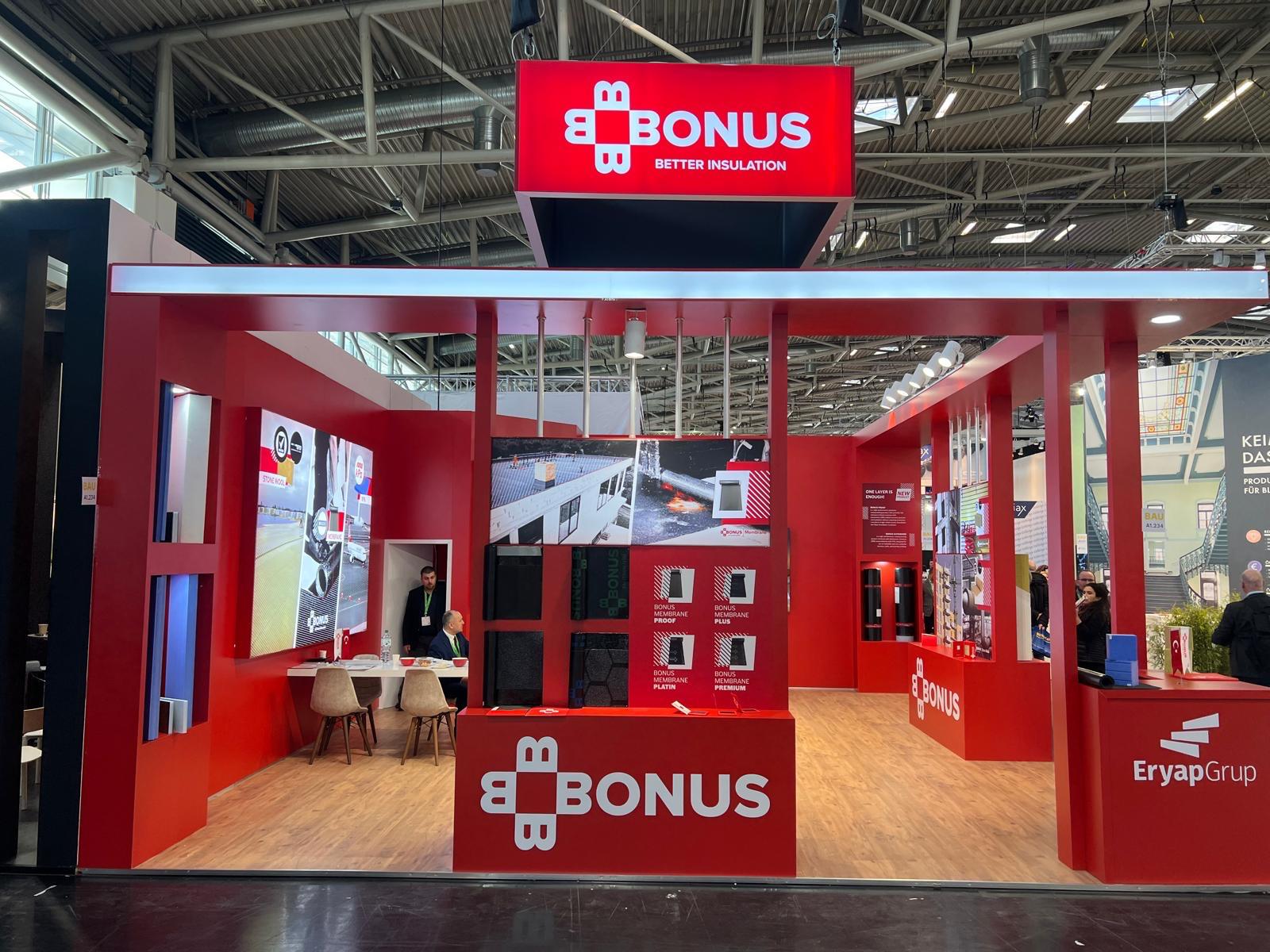 Four‑screen video wall at the BONUS stand, supporting product and application presentations for insulation solutions.