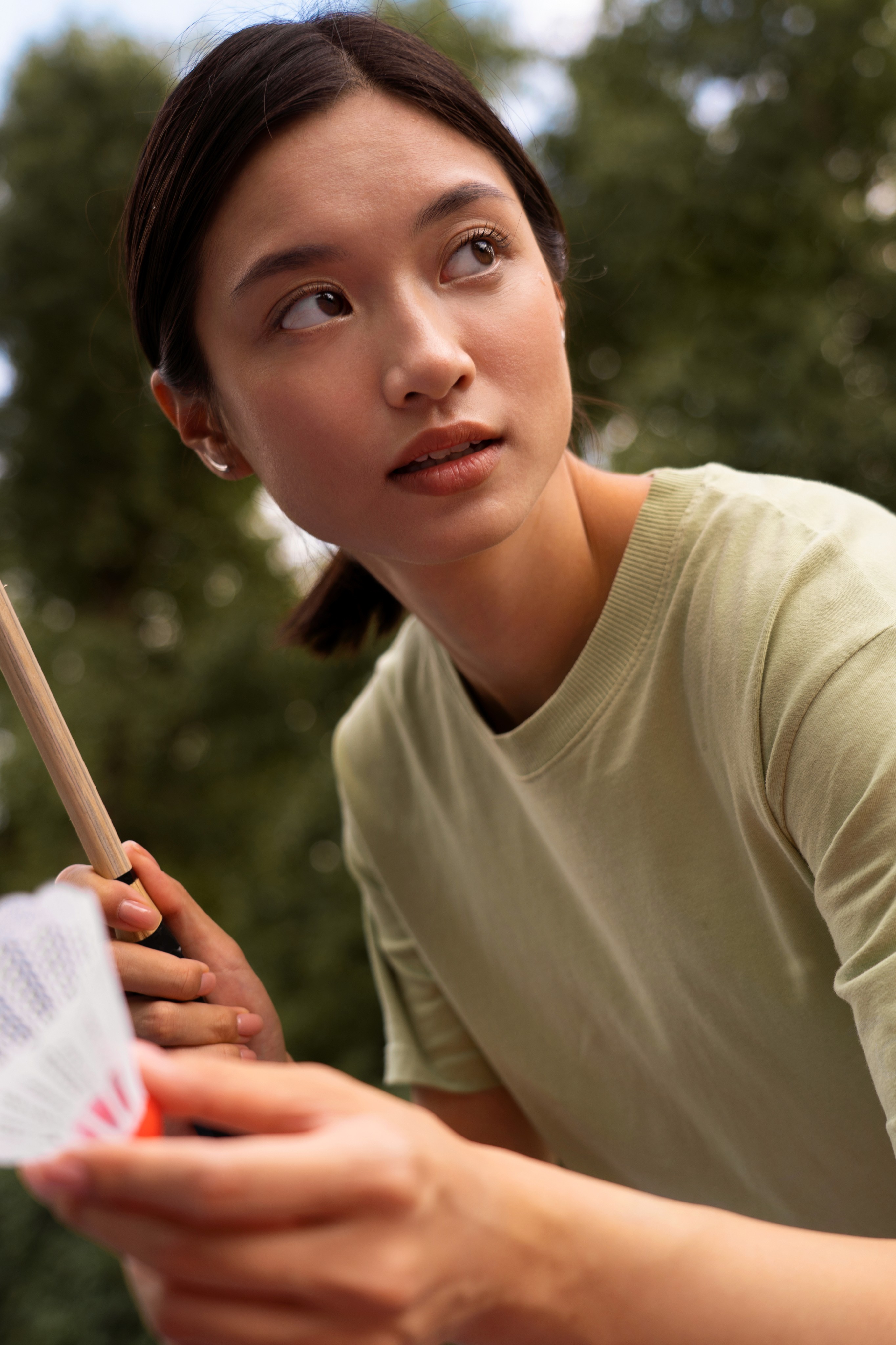 Woman outdoors holding a card and looking to the side.
