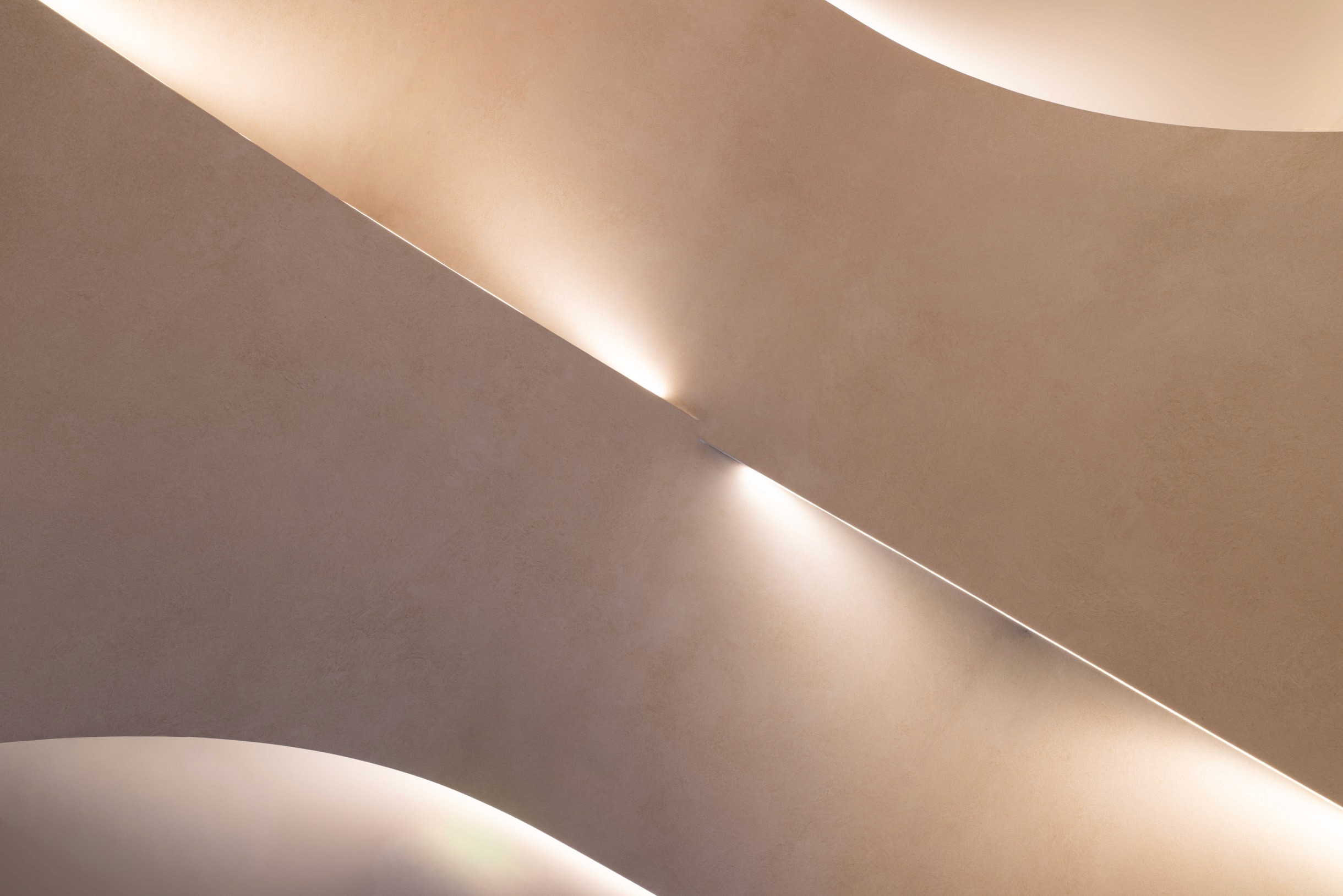 Detail of the integrated LED lighting, where light traces the seam of each curved plaster form.