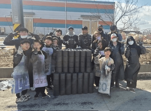 Up to Youth volunteers gathered beside coal briquettes