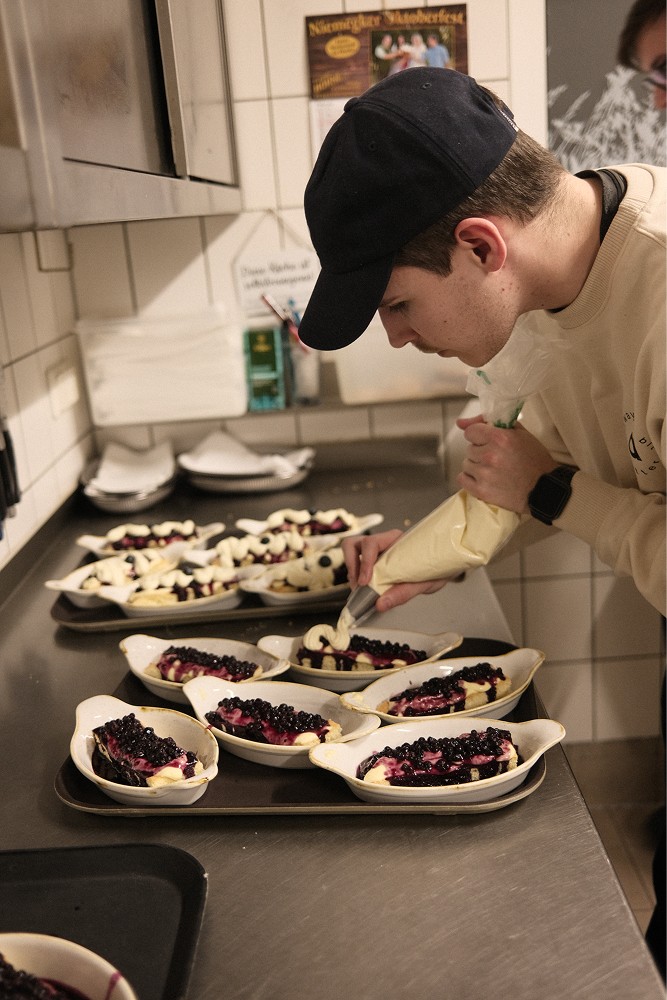 Mitarbeiter dekoriert mehrere Kuchen in einer Küche.