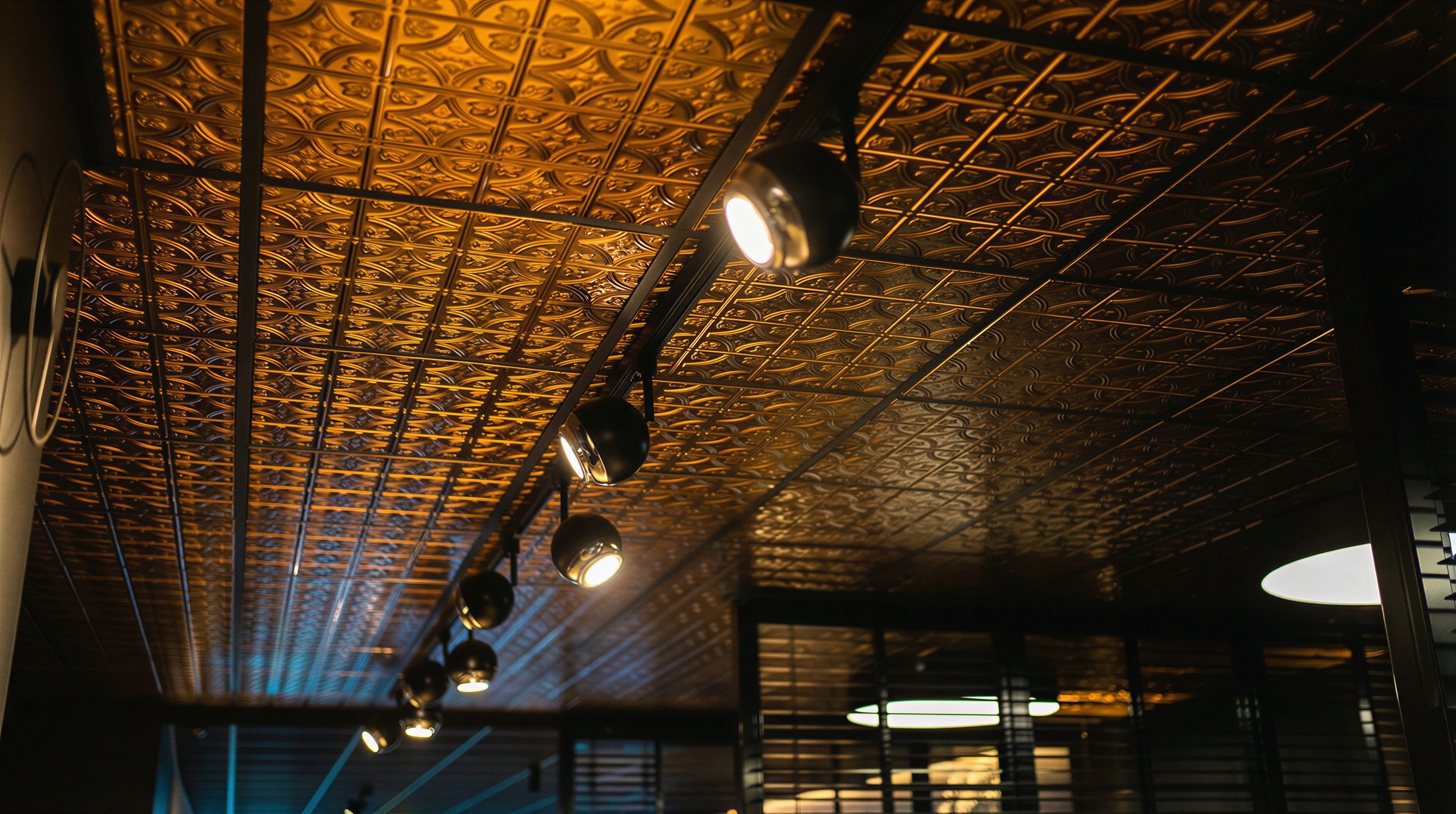 Custom koper-effect rasterplafond met functionele, verstelbare track-lighting voor optimaal werklicht in de tattoo studio.