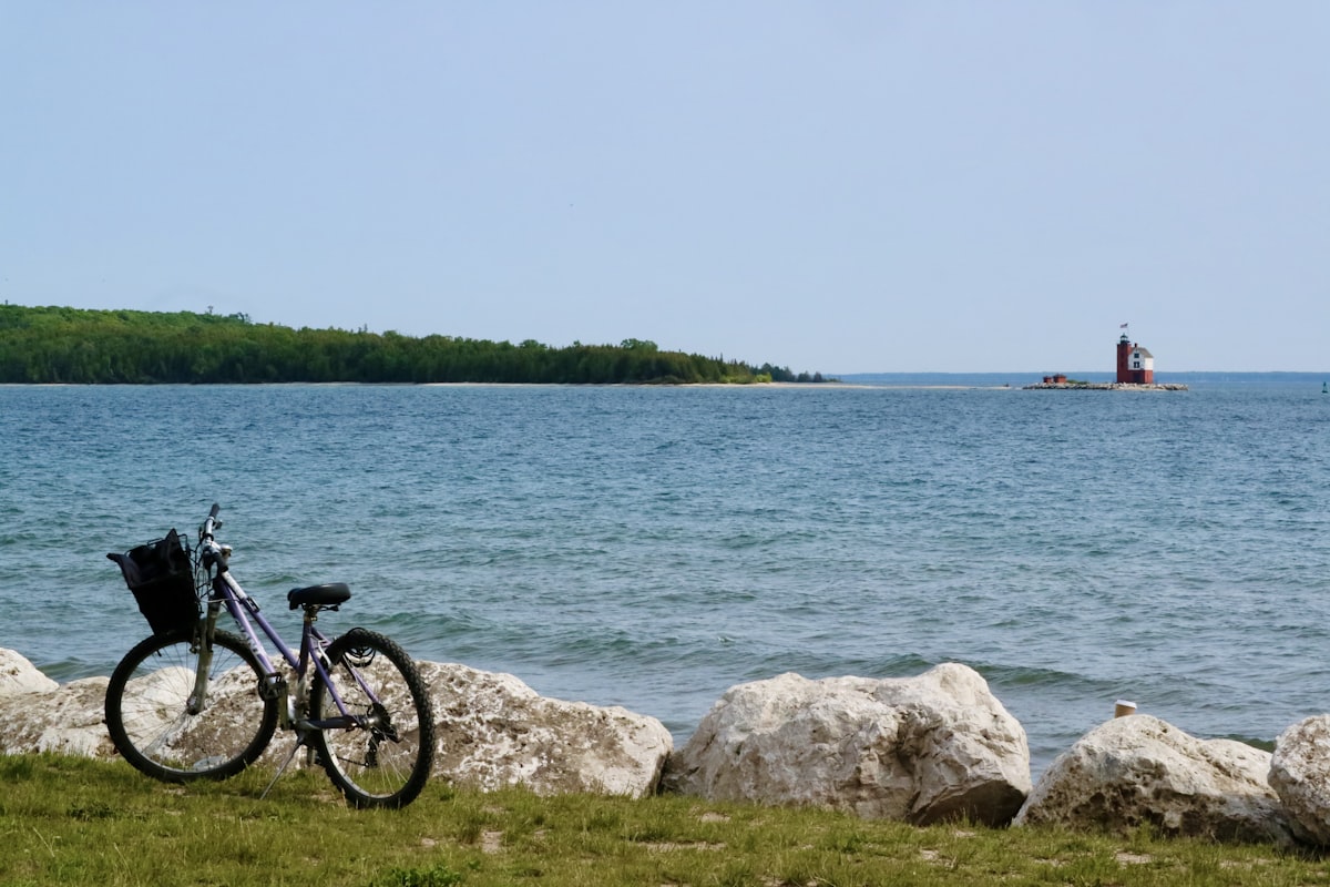 Bicycle resting by the Great Lakes shoreline with a lighthouse on Mackinac Island, Michigan