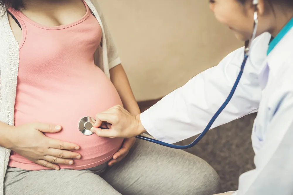 Doctor listening to a pregnant woman's belly with a stethoscope