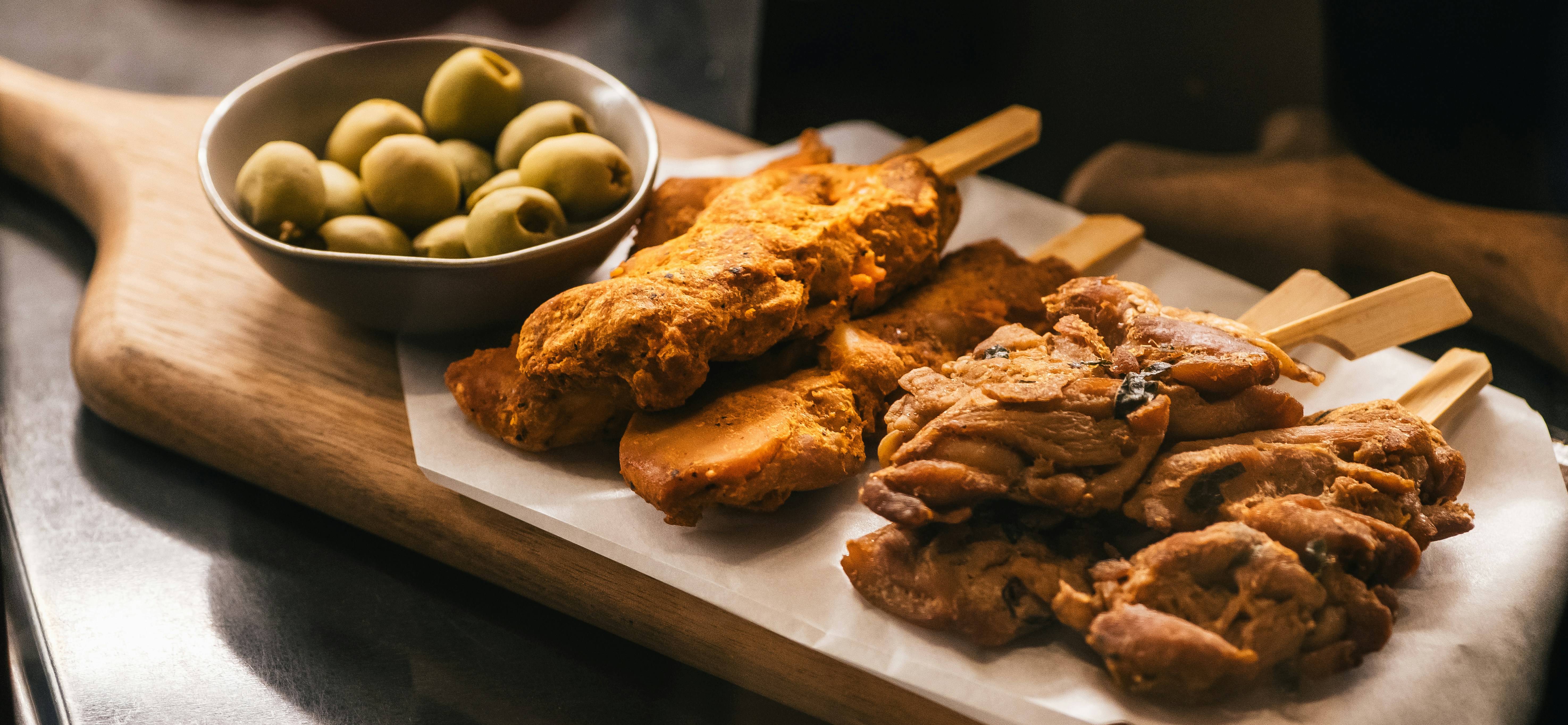 A wooden cutting board topped with meat and veggies