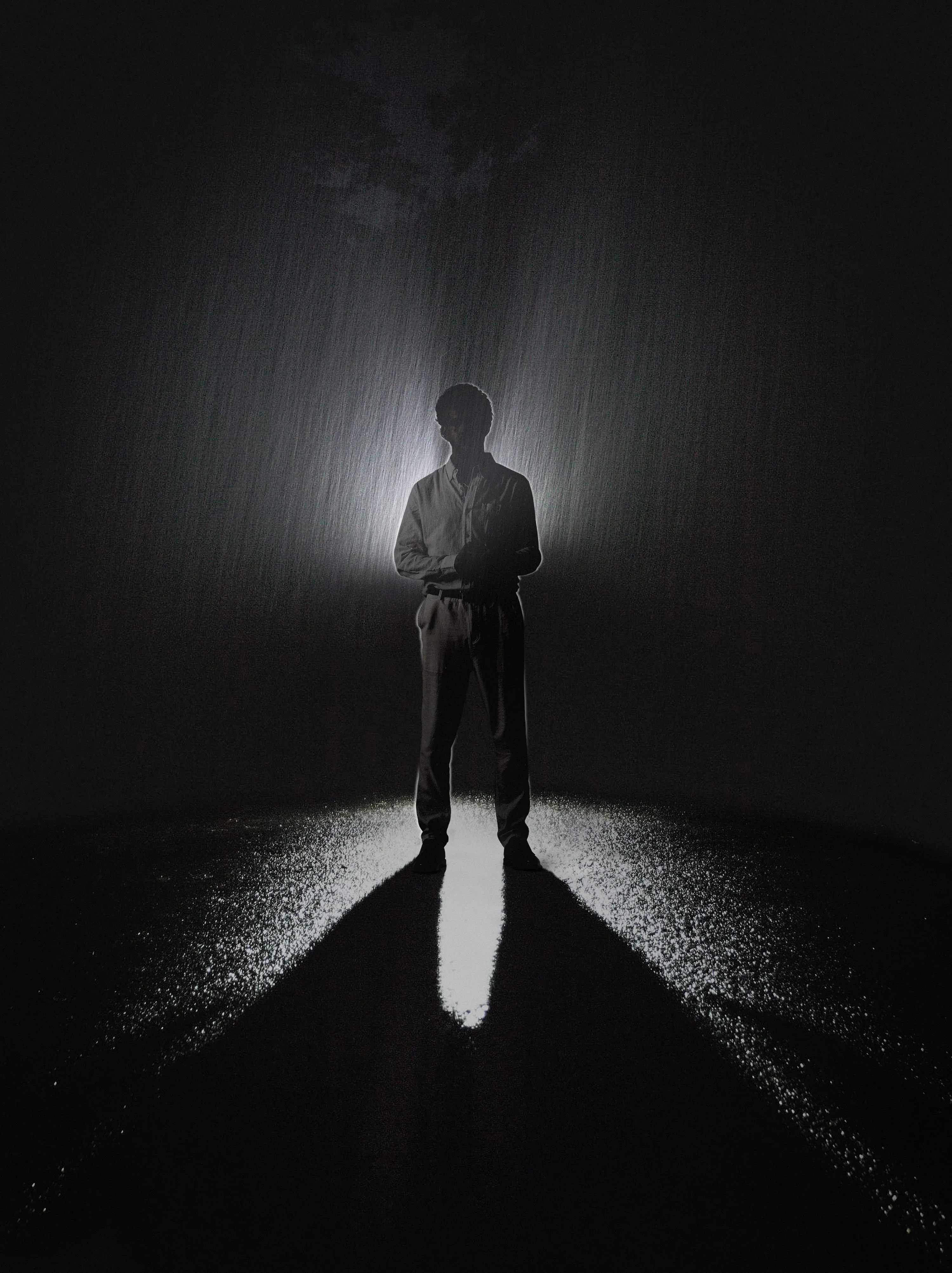 Silhouette of Jeffrey Hakim standing in a single beam of light on a dark, rainy night.