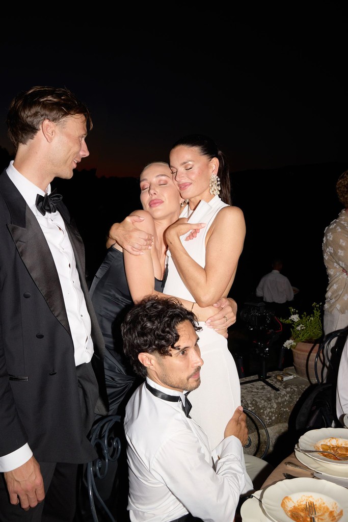 Best friend of bride hugging her with closed eyes and guests smiling at them