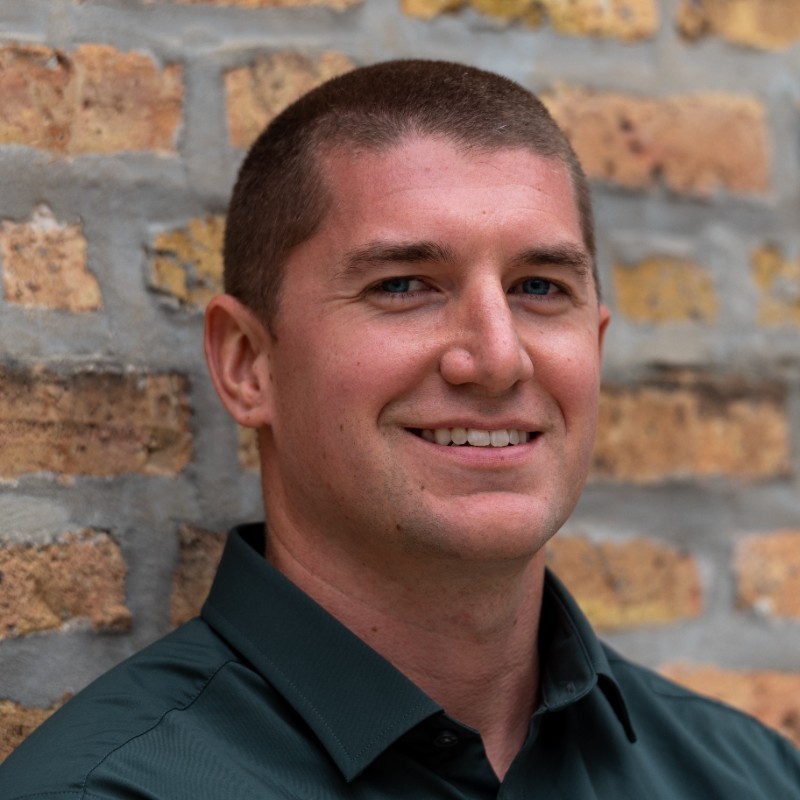 Man poses in front of brick wall