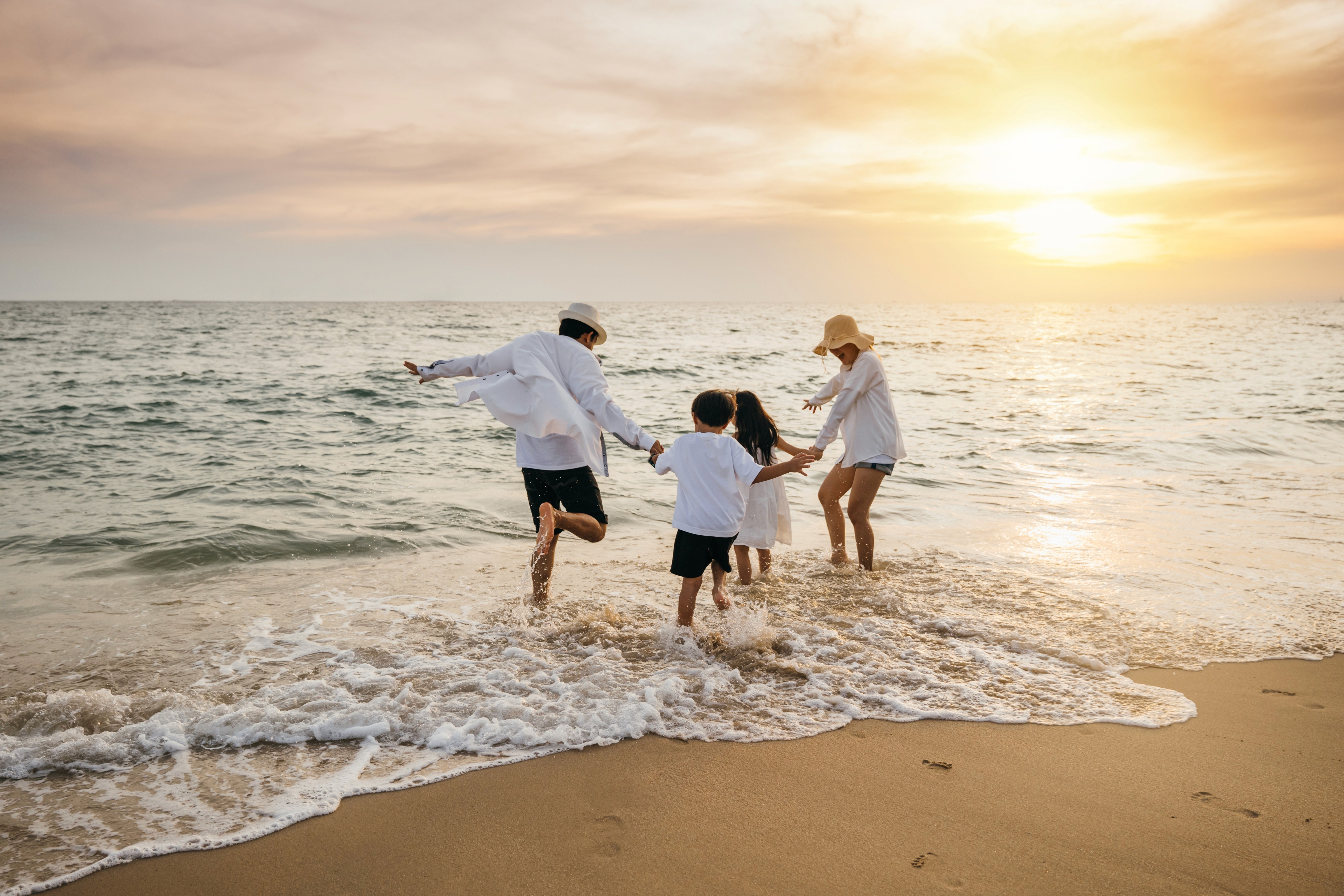 A family playing in the water on a beach during sunset