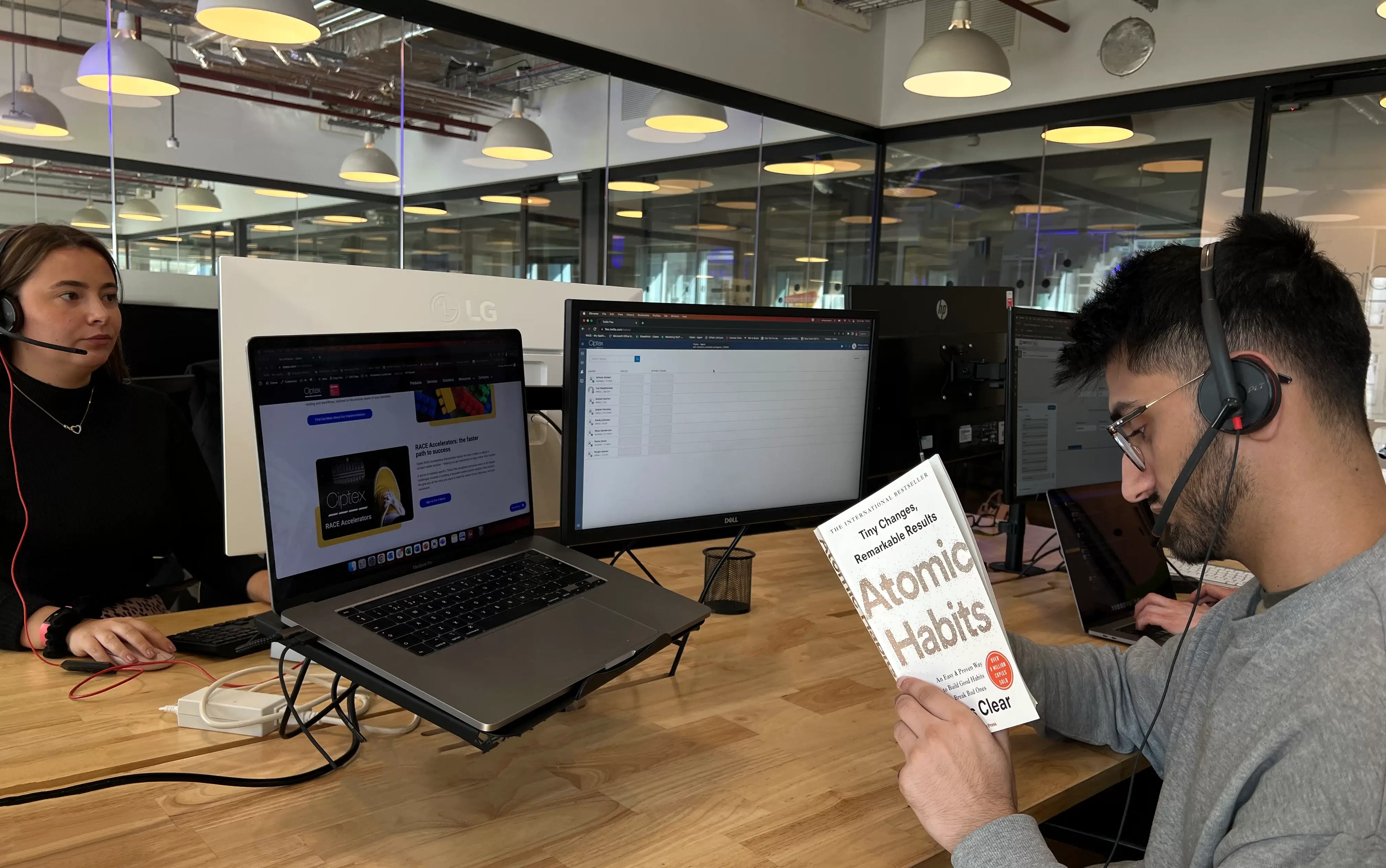 Image of a young man sat at a desk reading the book Atomic Habits.