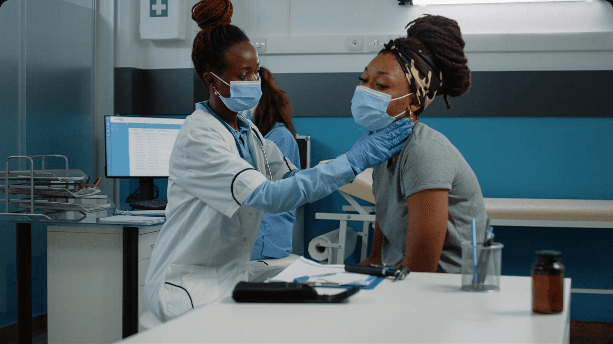 Male doctor examining little girl holding teddy bear toy