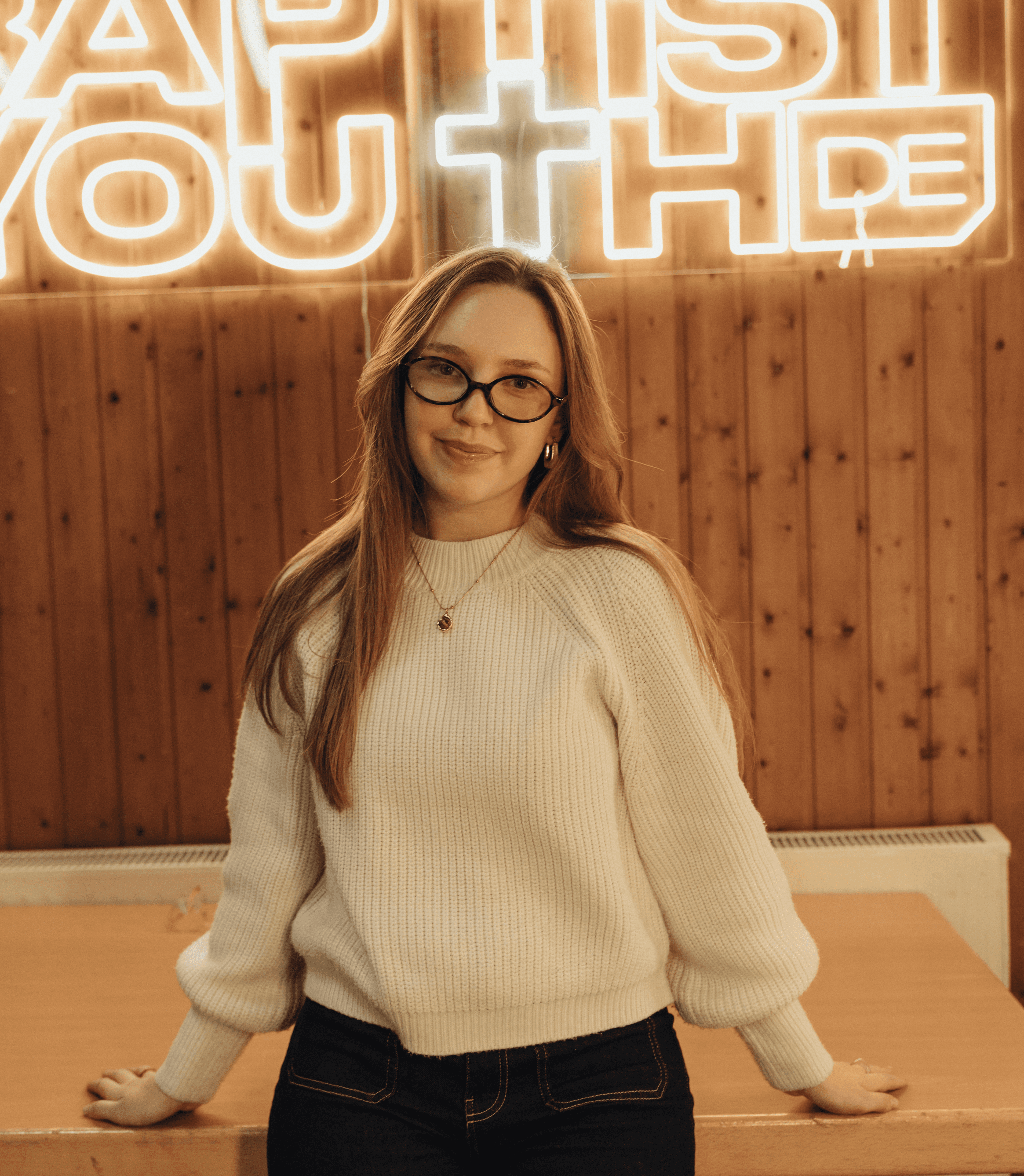 A thoughtful young person with dark hair gazes to the side, captured in soft black and white lighting.