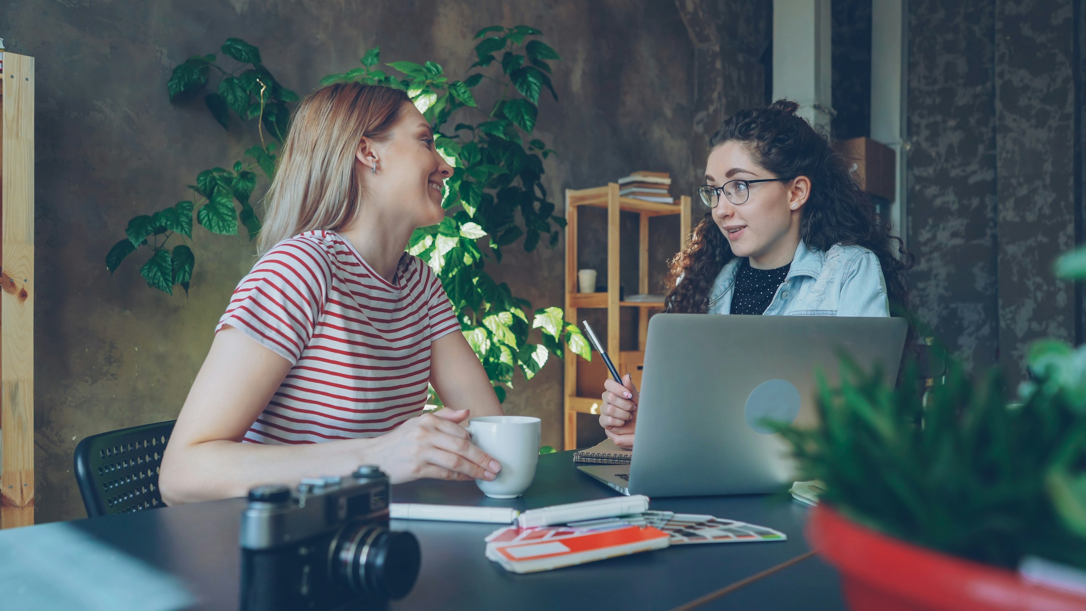 Two women discuss over a laptop.