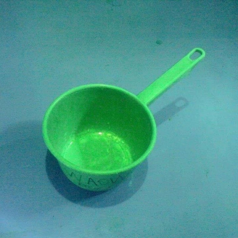 Ciduk Warrior, a green plastic measuring cup, sitting on a blue surface.