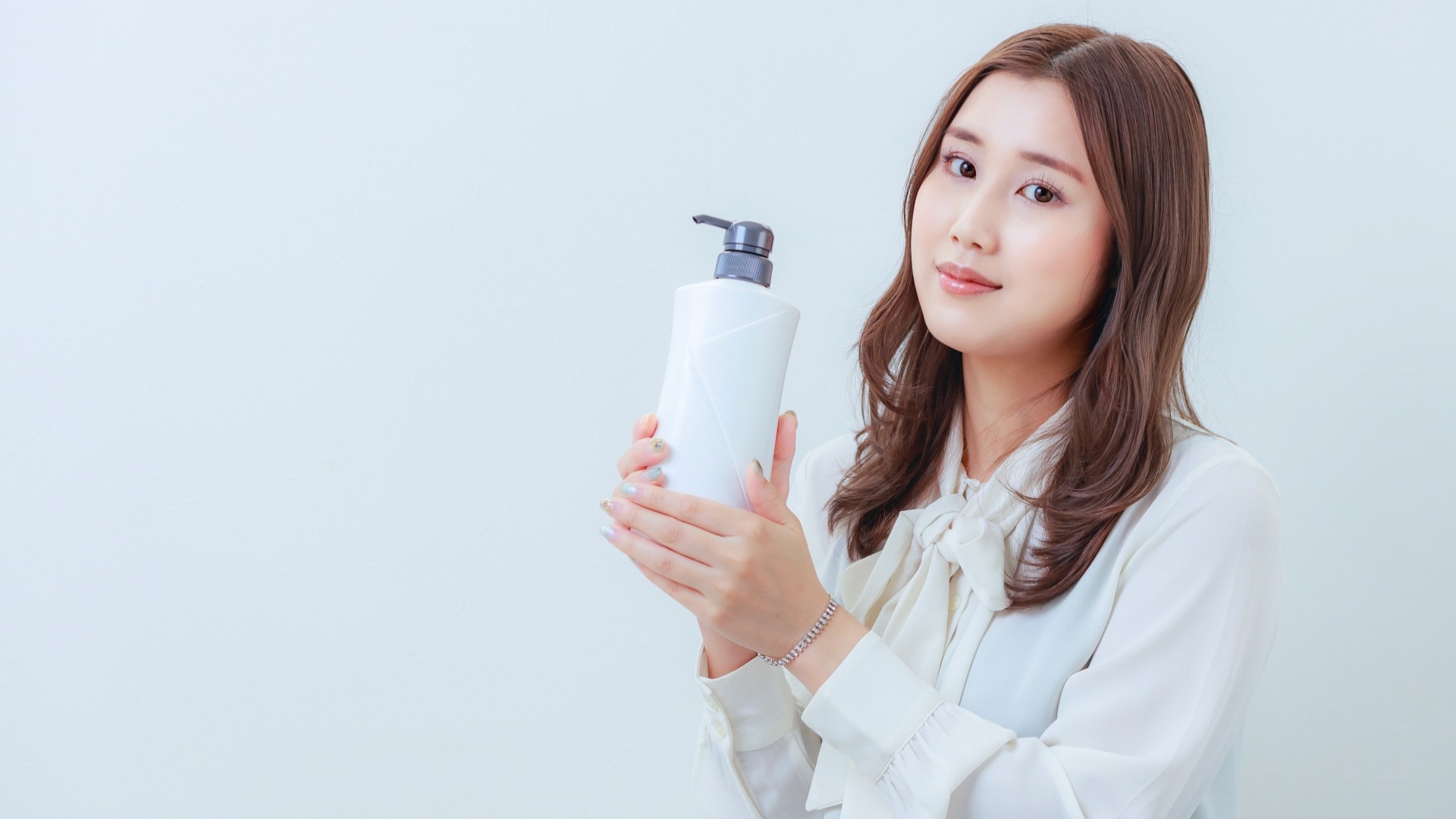 白色のシャンプーを持ったカメラ目線の女性