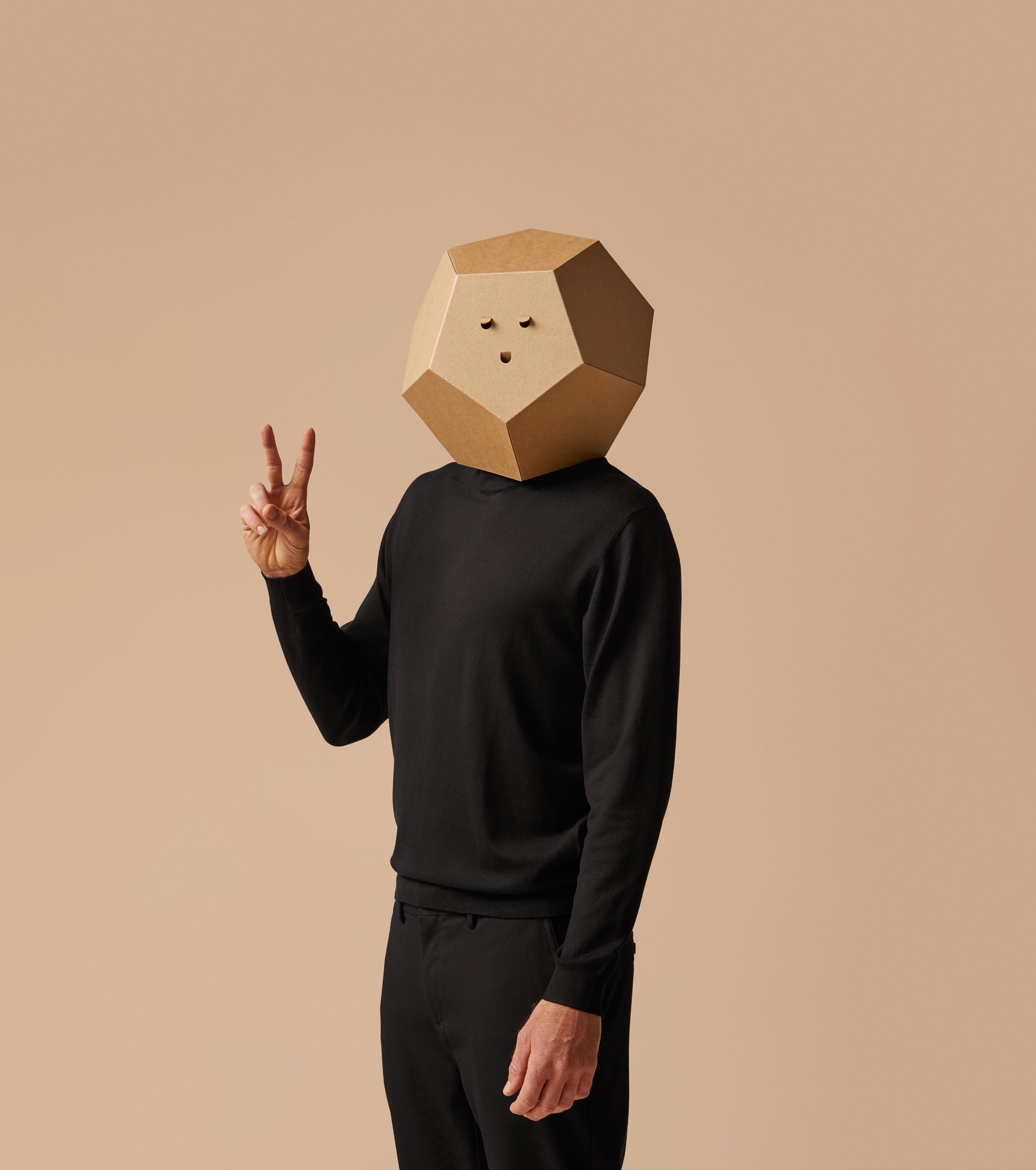 Person wearing a geometric cardboard mask and black clothing