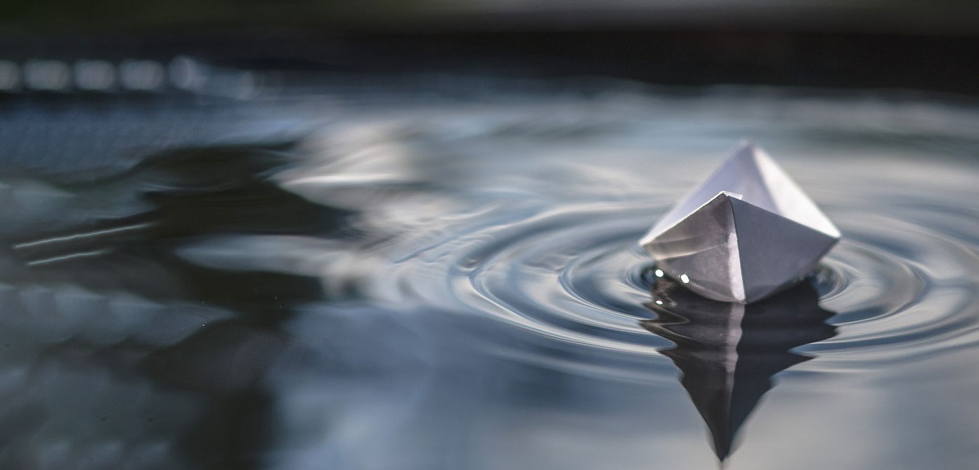 Close-up of a scientist holding a tray of petri dishes with purple cultures, wearing gloves and safety gear.
