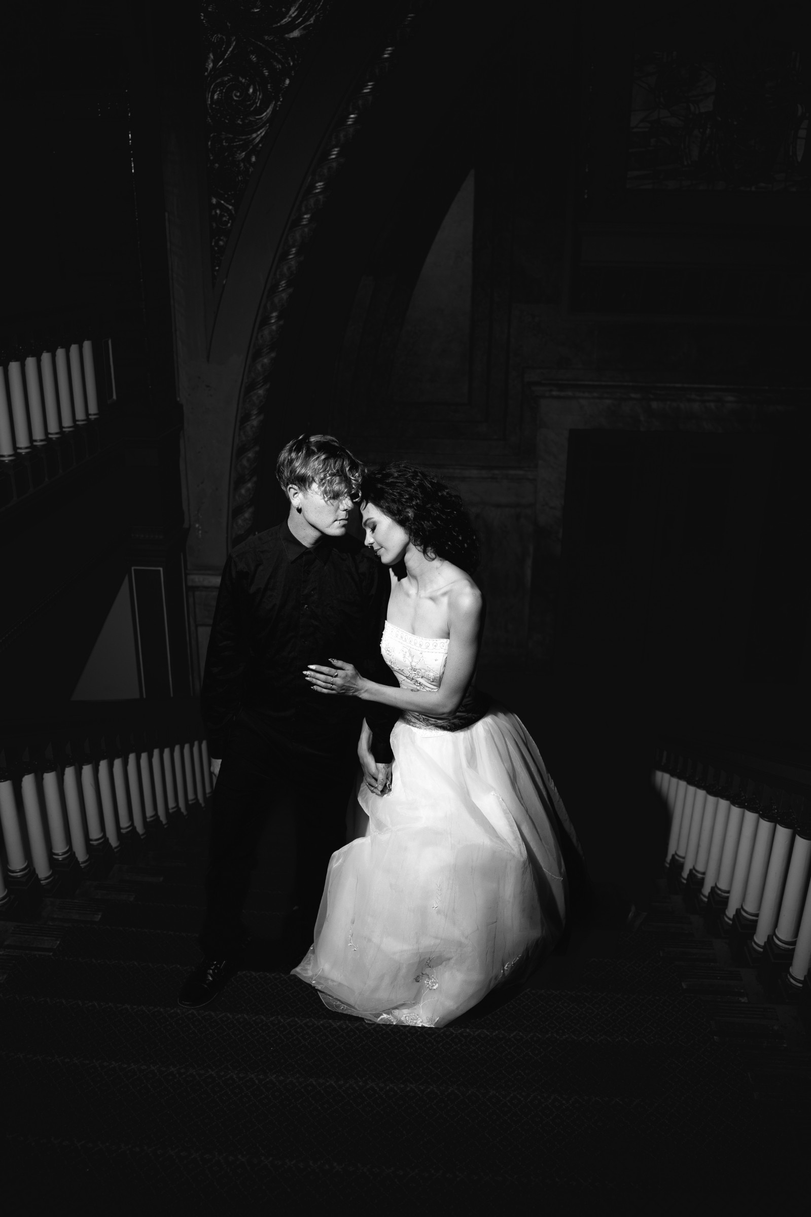 A bride and groom share a kiss surrounded by a joyful bridal party.