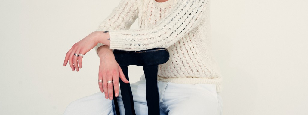 Color close-up of the hands of a young blonde tattooed man sitting on a chair