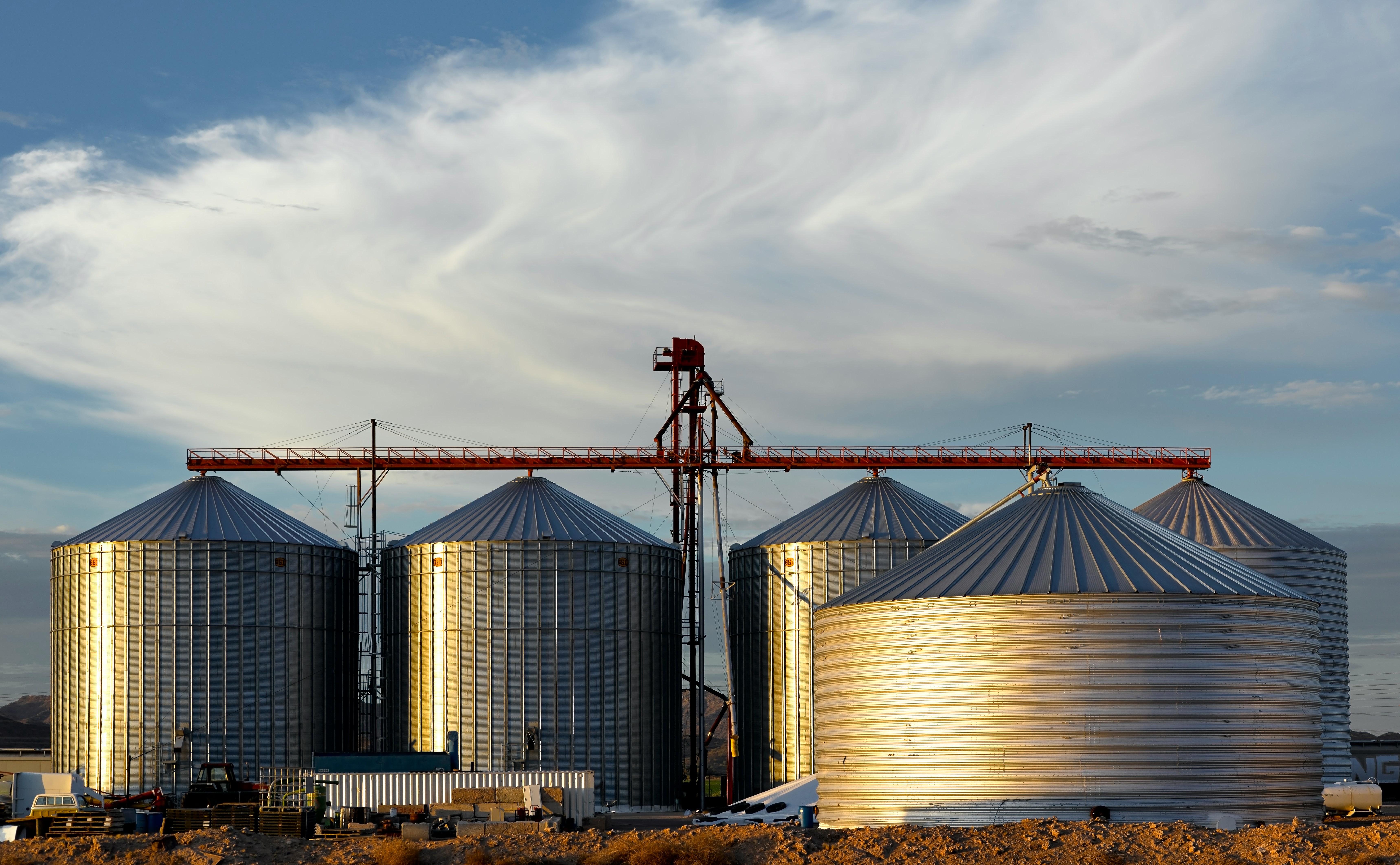 Row of steel grain bins with auger loading equipment at a farm