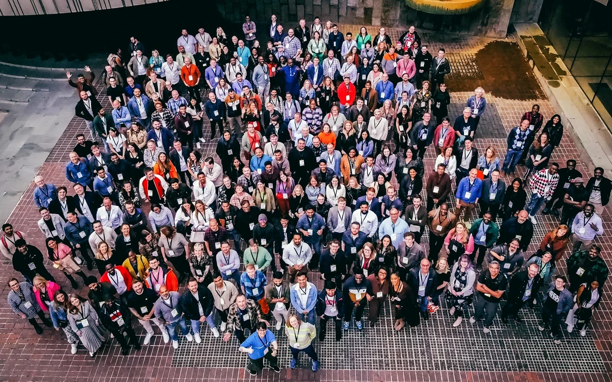 A large group of people in an outside space looking up towards the camera above them