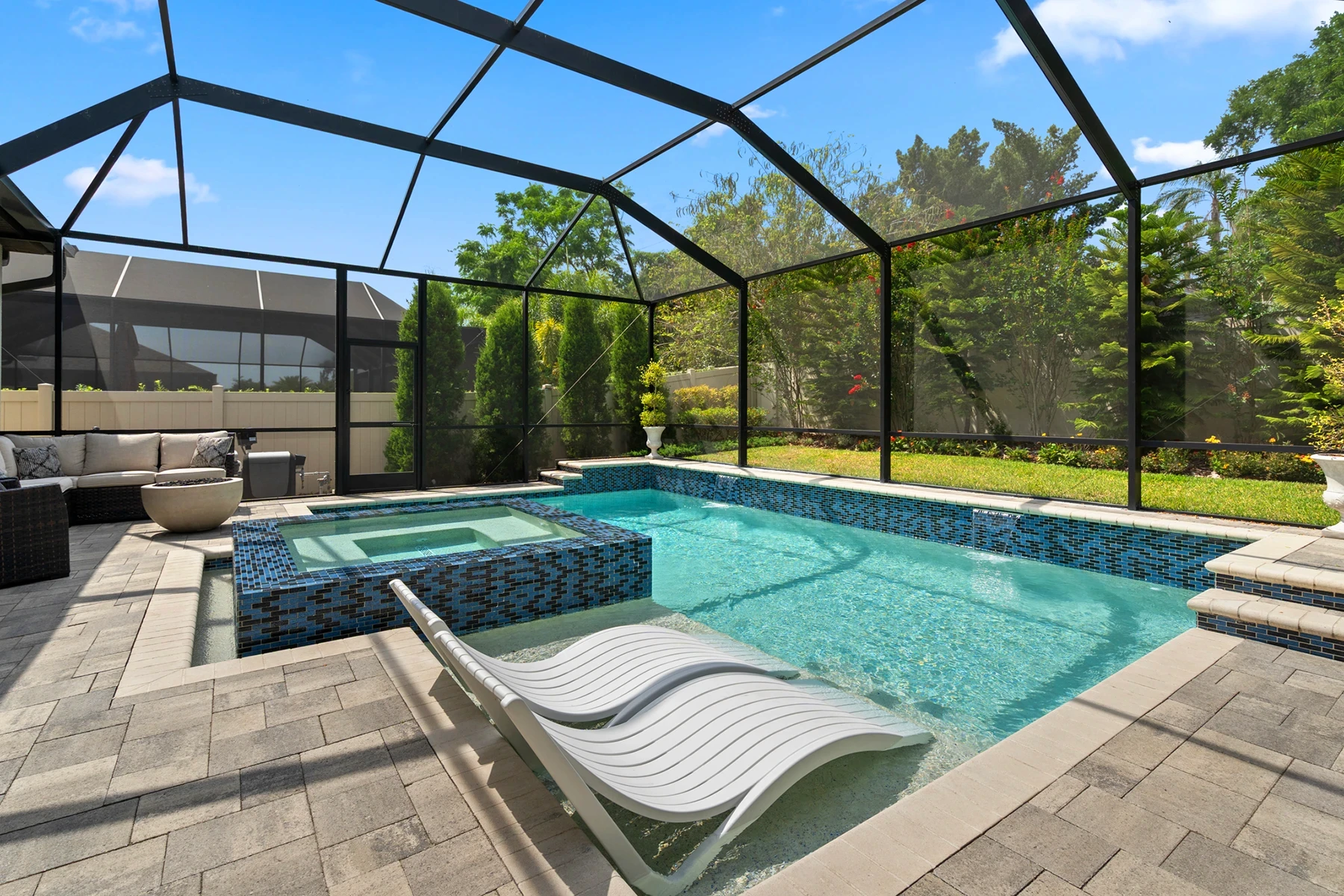 Screen-enclosed pool with spa, lounge chairs and paver deck at a Brandon, FL home