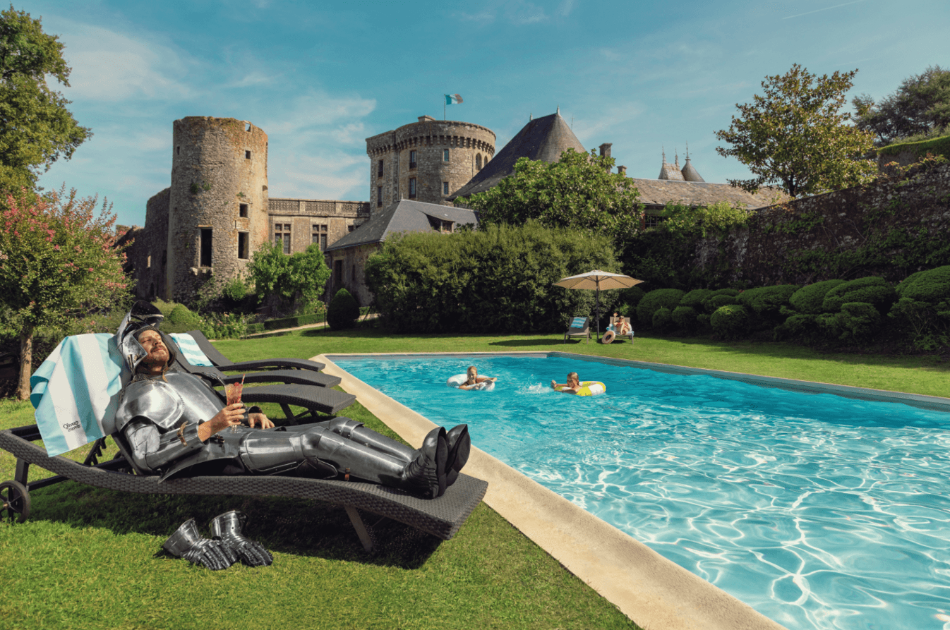 Person wearing a backpack standing near a steaming geothermal area with rocky cliffs in the background, featuring Channel 4 Escapism and Fred.Olsen Cruise Lines branding.