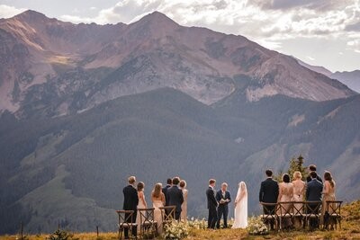 A wide view of the intimate ceremony and standing guests beneath a rugged mountain peak.