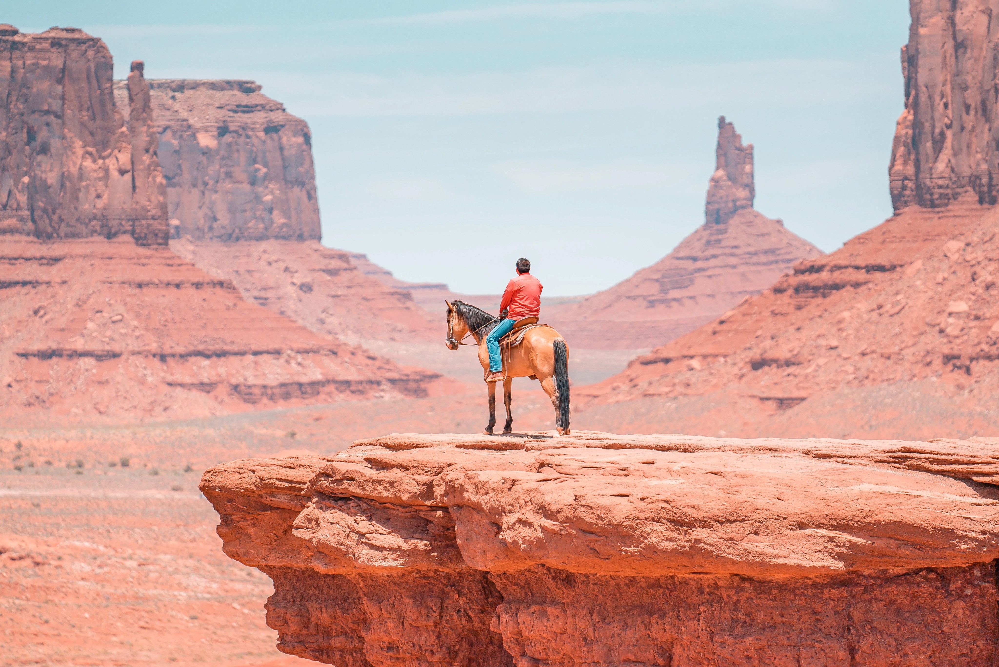 A man on a horse looking out over colorado dessert with strange mountain formations