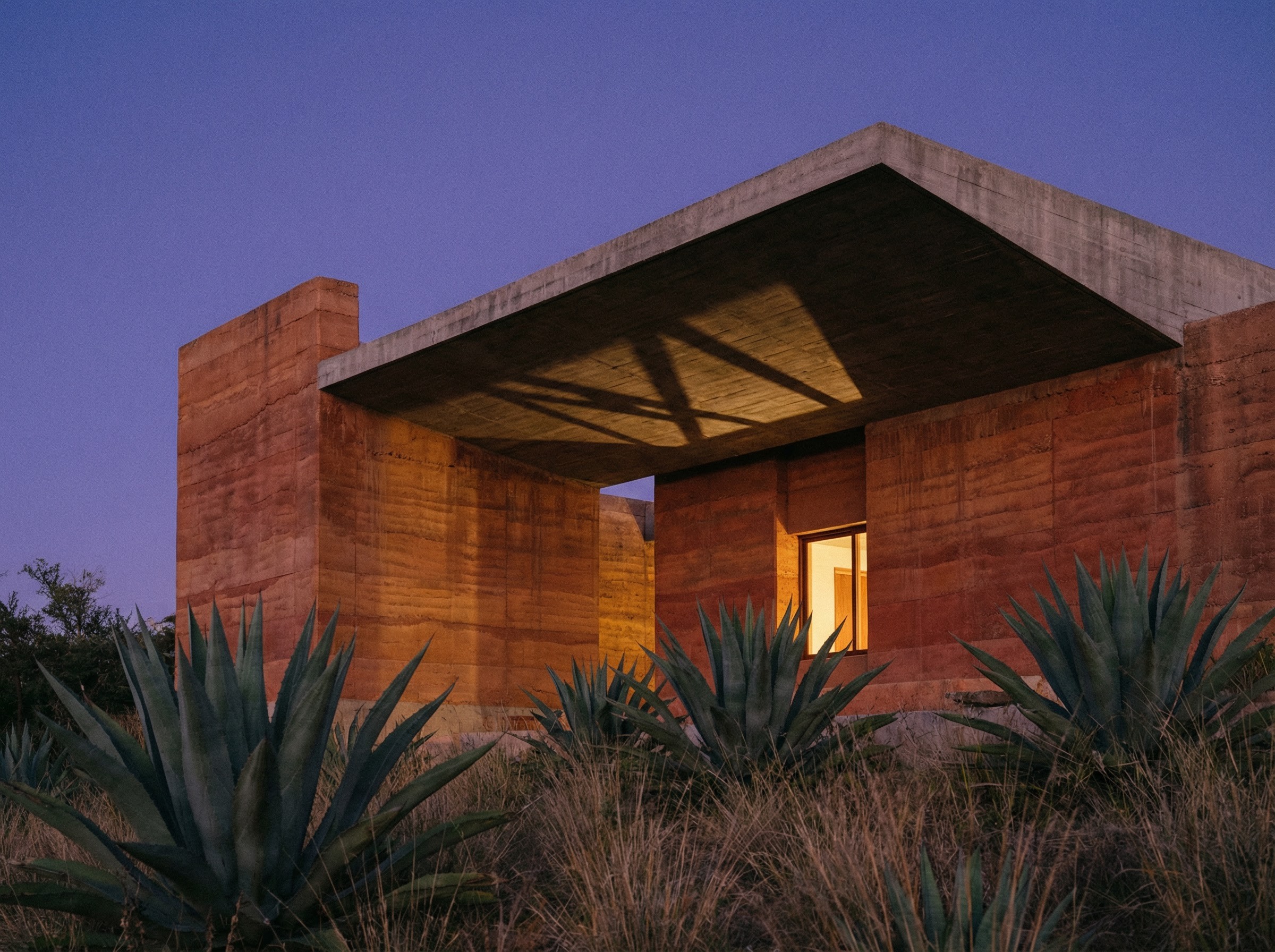 Modern concrete and rammed earth house at dusk