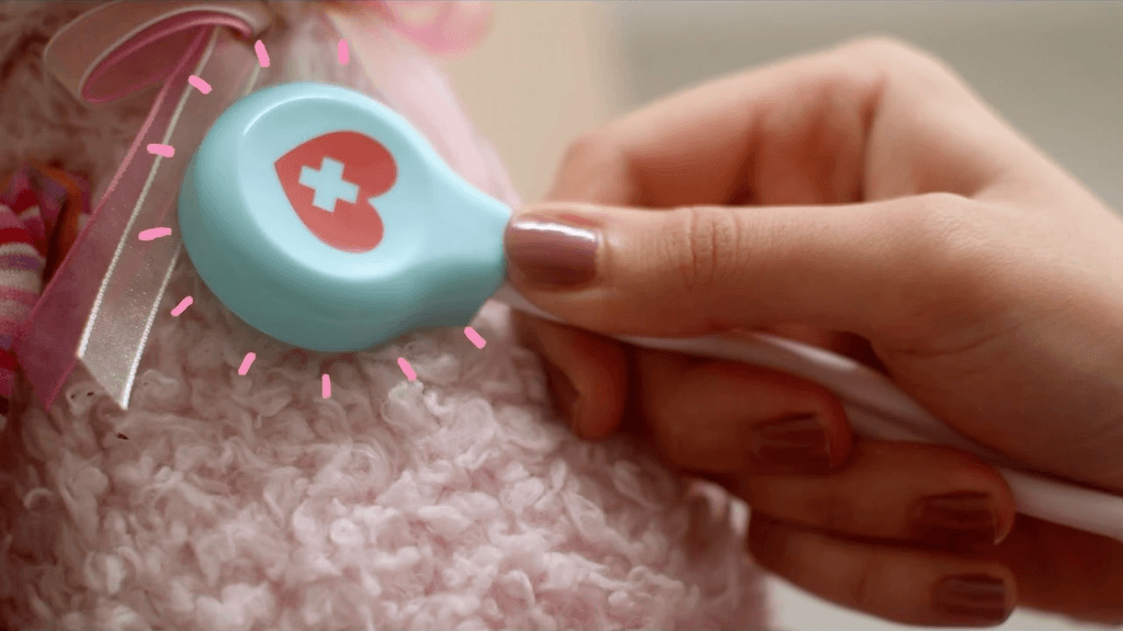 Screenshot from the ad, showing the doctor holding a toy stethoscope to the stuffed bunny's heart, with emphasis lines coming from it (my animations).