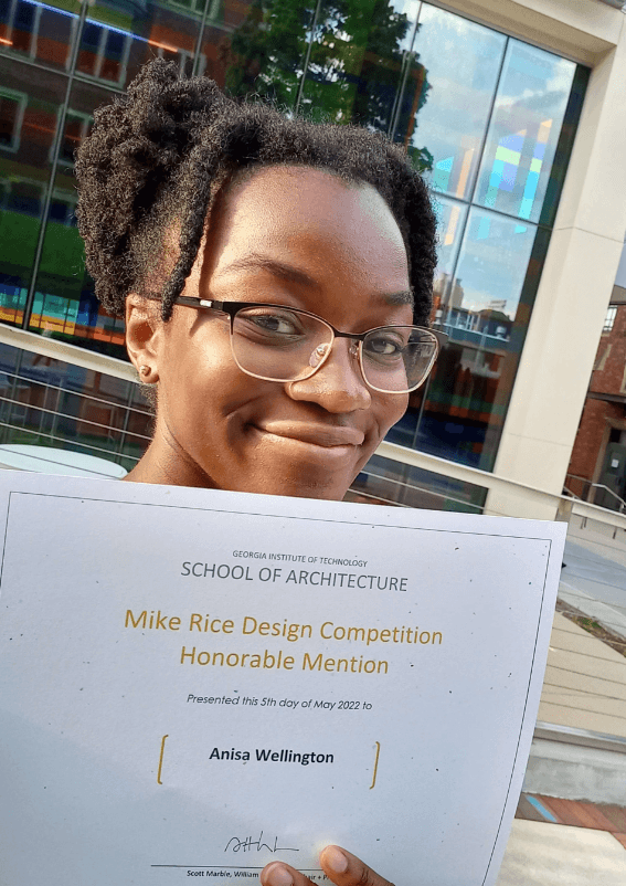 Anisa Wellington holding a certificate for the Mike Rice Design Competition.