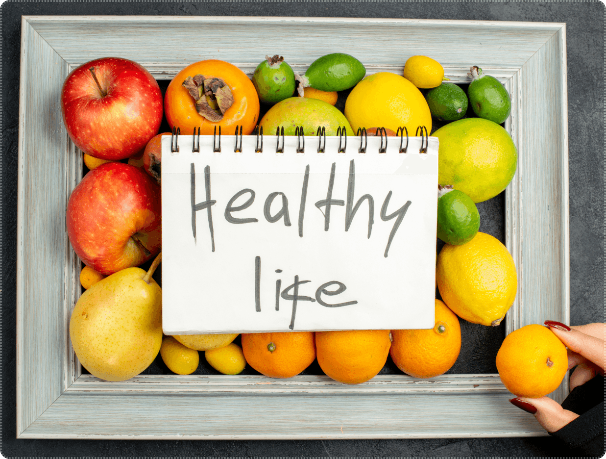 Fresh fruit and citrus arranged around a notepad with the words Healthy Life, promoting healthy eating at Kaleidoscope Kids childcare.