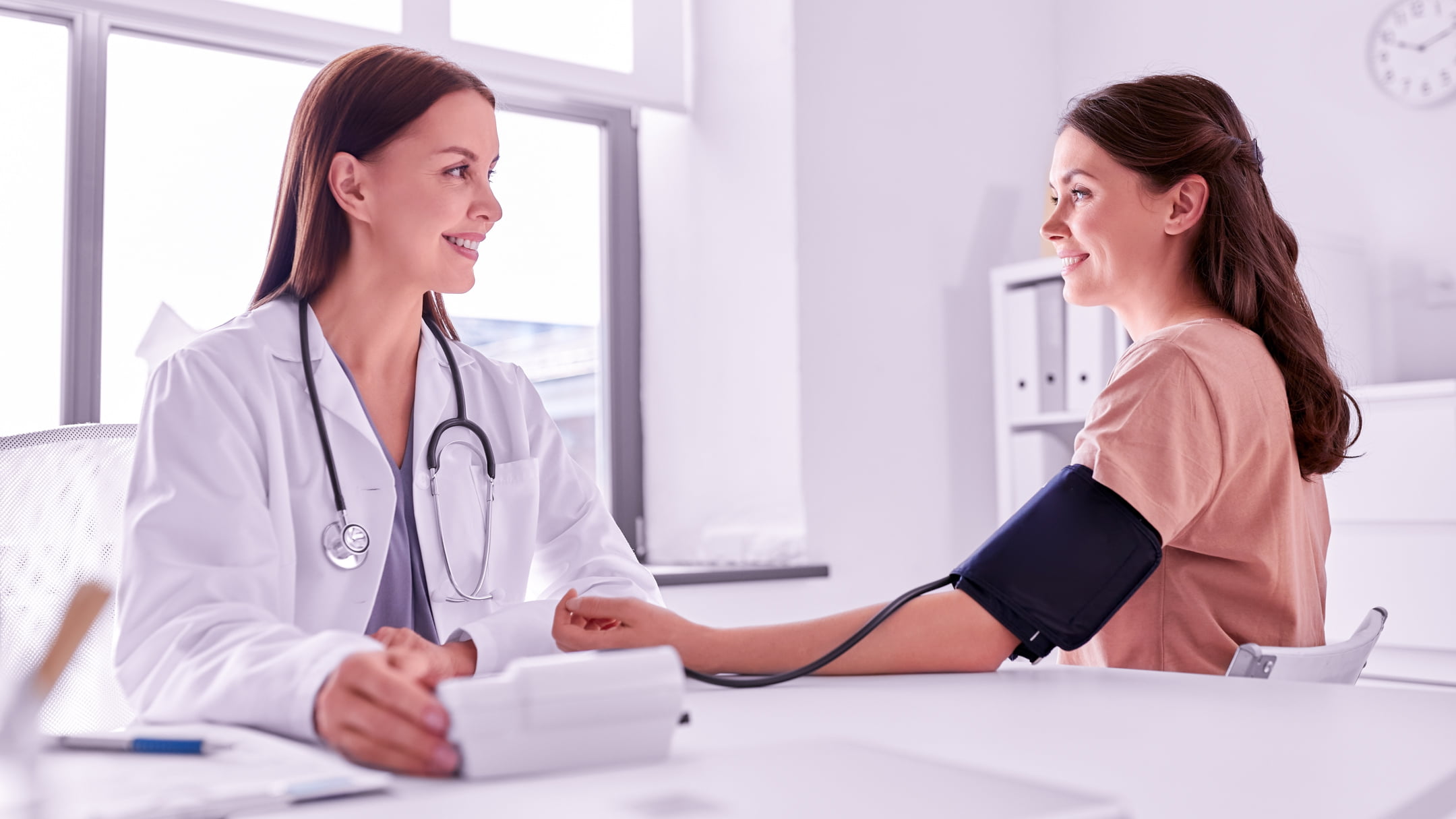 Women having blood pressure tested by a doctor