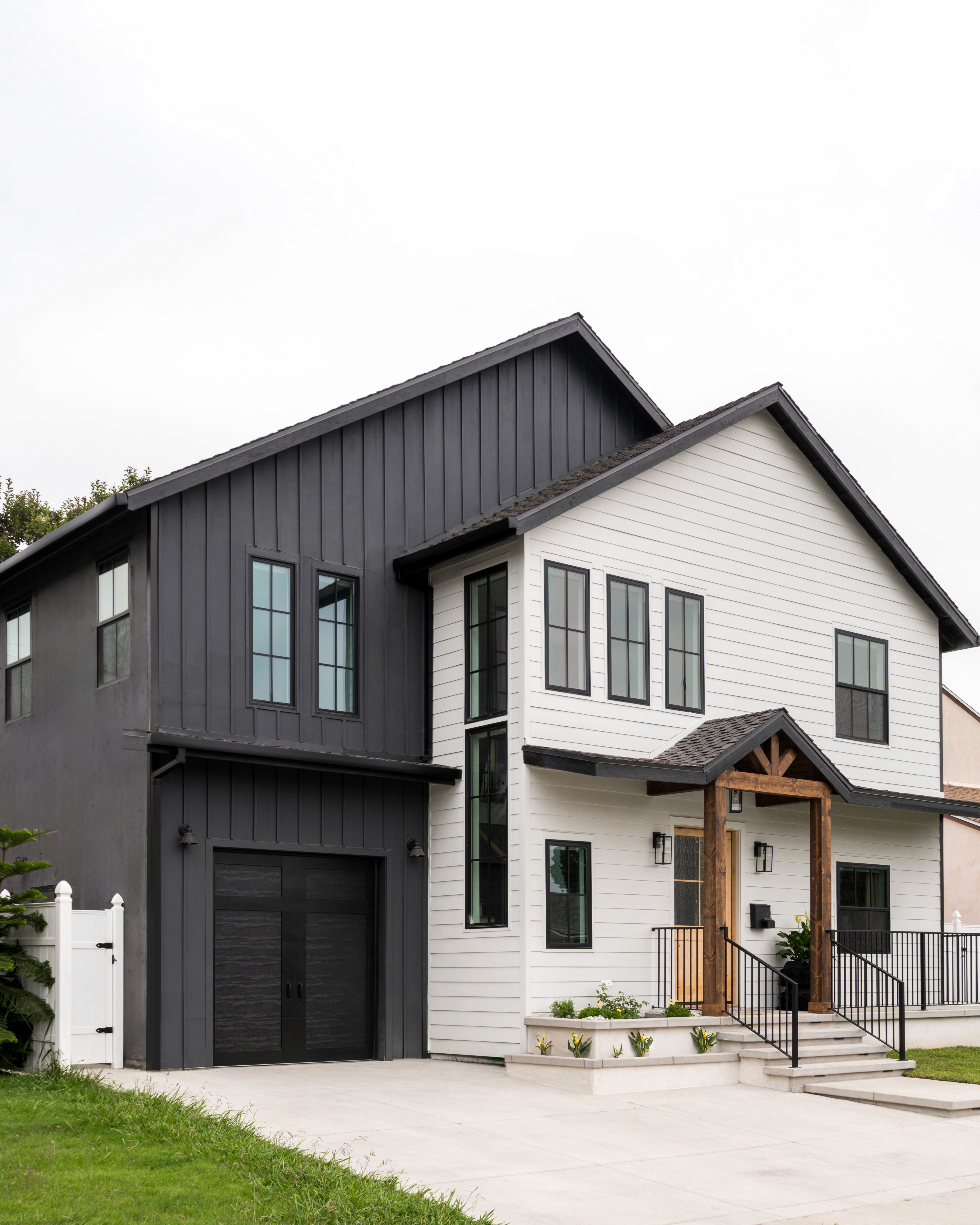 A two-story home with white siding and warm wood accents by Jubilee Interiors located in Westlake Village, CA