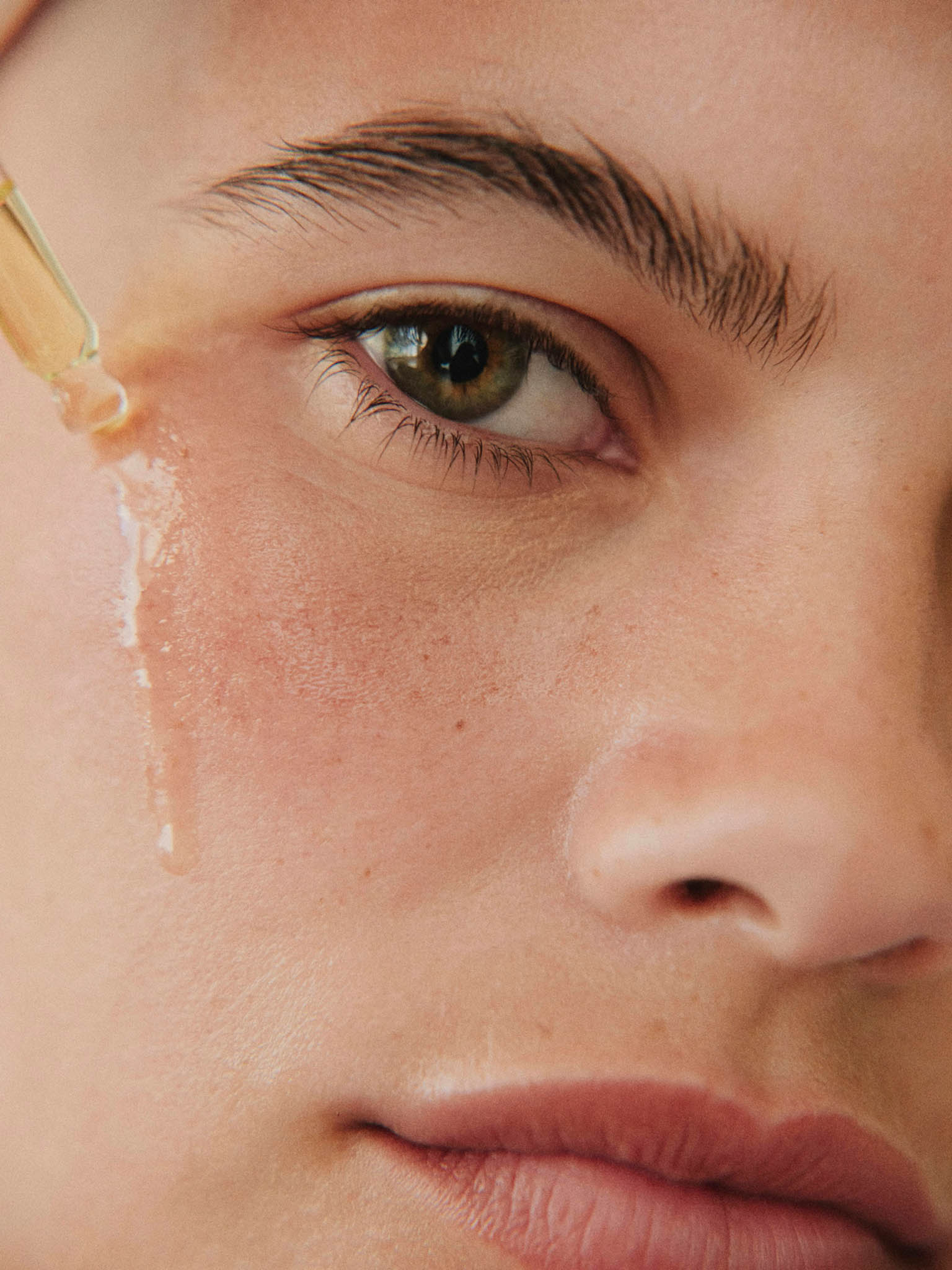 close up visage d'une femme appliquant du serum sur la joue