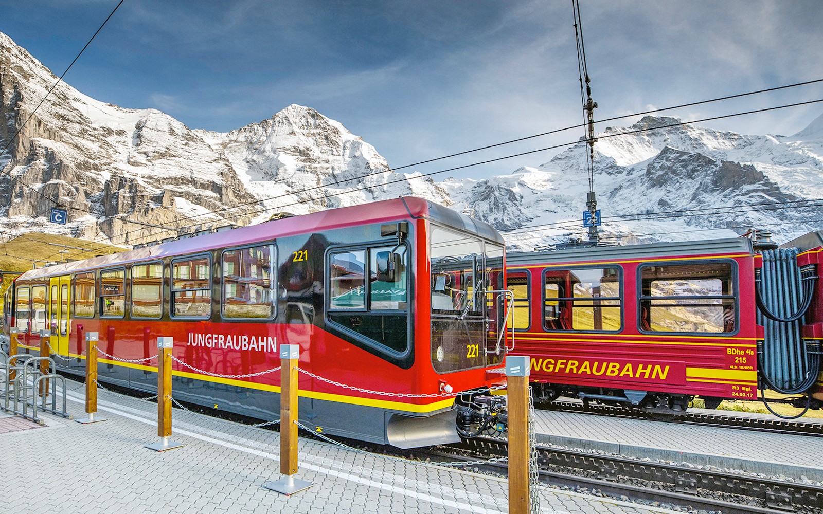 Jungfraubahn-tåg vid stationen med snötäckta berg i Berner Oberland, Schweiz.