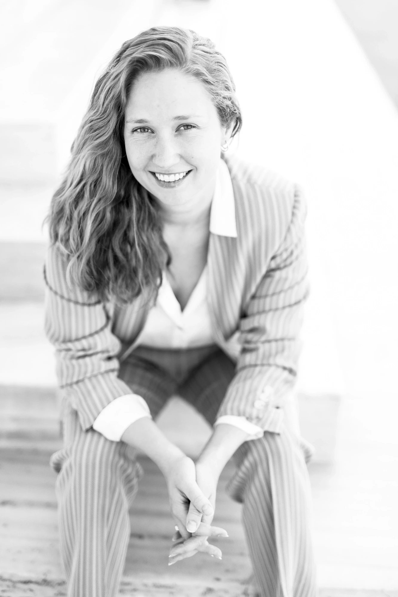 Black and white portrait of Lindsay E. Lynch, editor and writer at Sense and Syntax, smiling while seated outdoors.