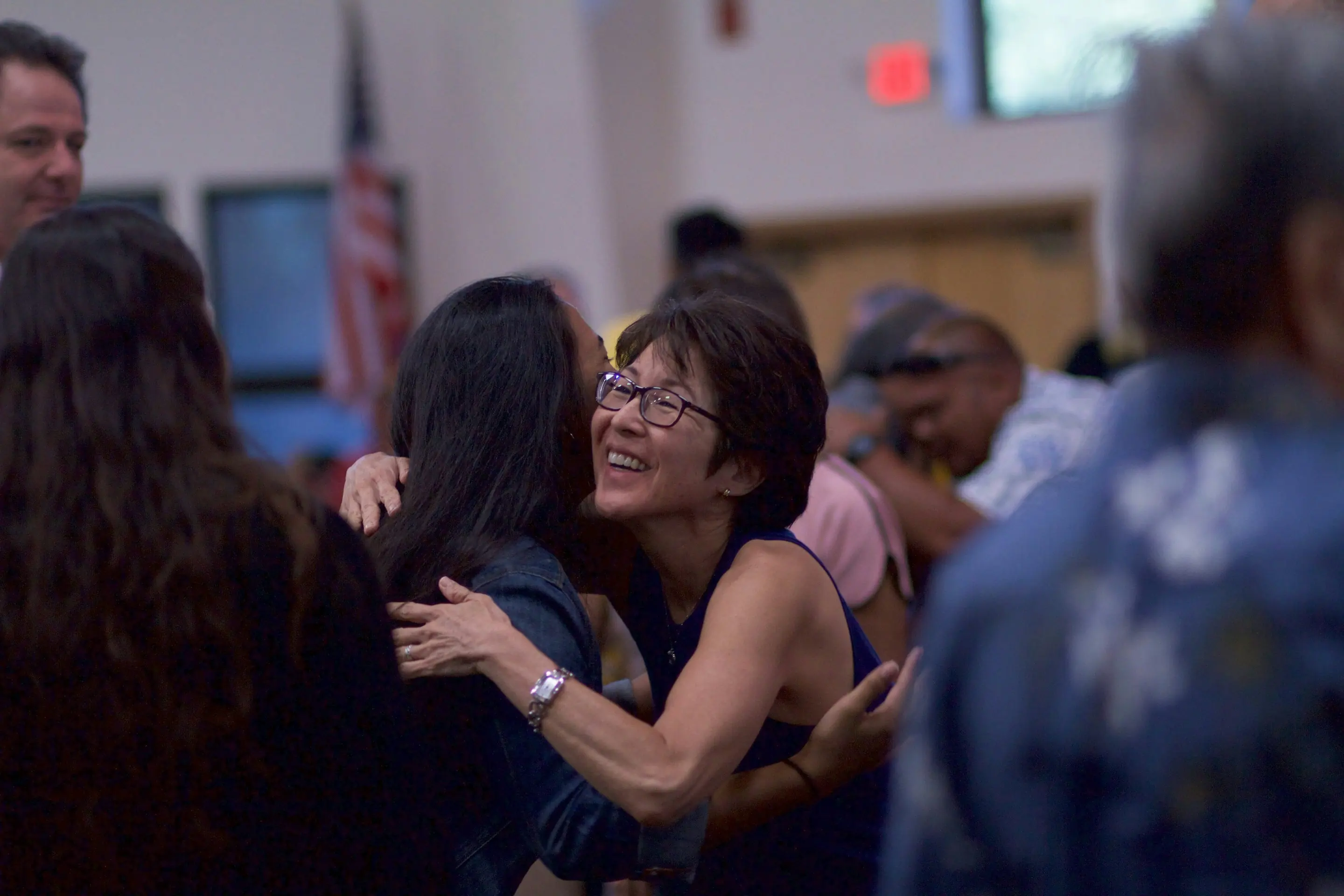 Two women hugging hello before a Sunday gathering